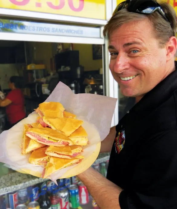 A smiling Gus Moore serving empanadas on the street