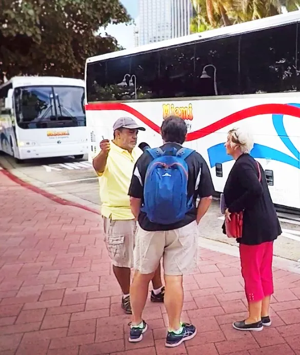 A tour guide helping two elderly customers board the bus