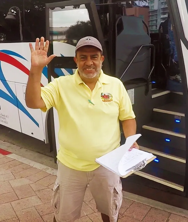 A smiling tour guide greeting customers near the bus