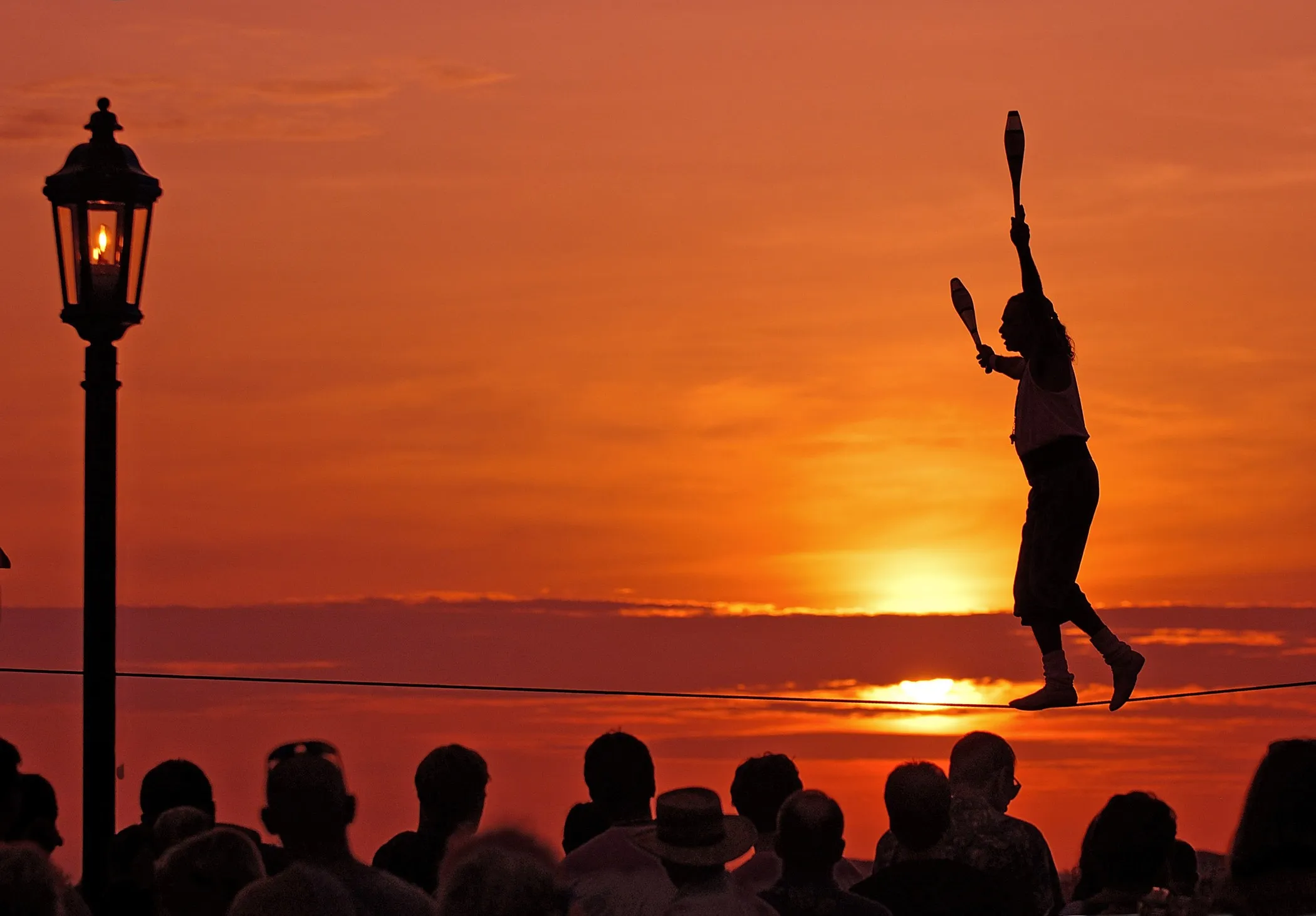 Tightrope walker in silhouette perming at sunset on Mallory Square