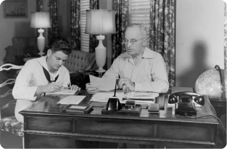 Black and white photo of President Truman and a Navy sailor inside the Little White House.