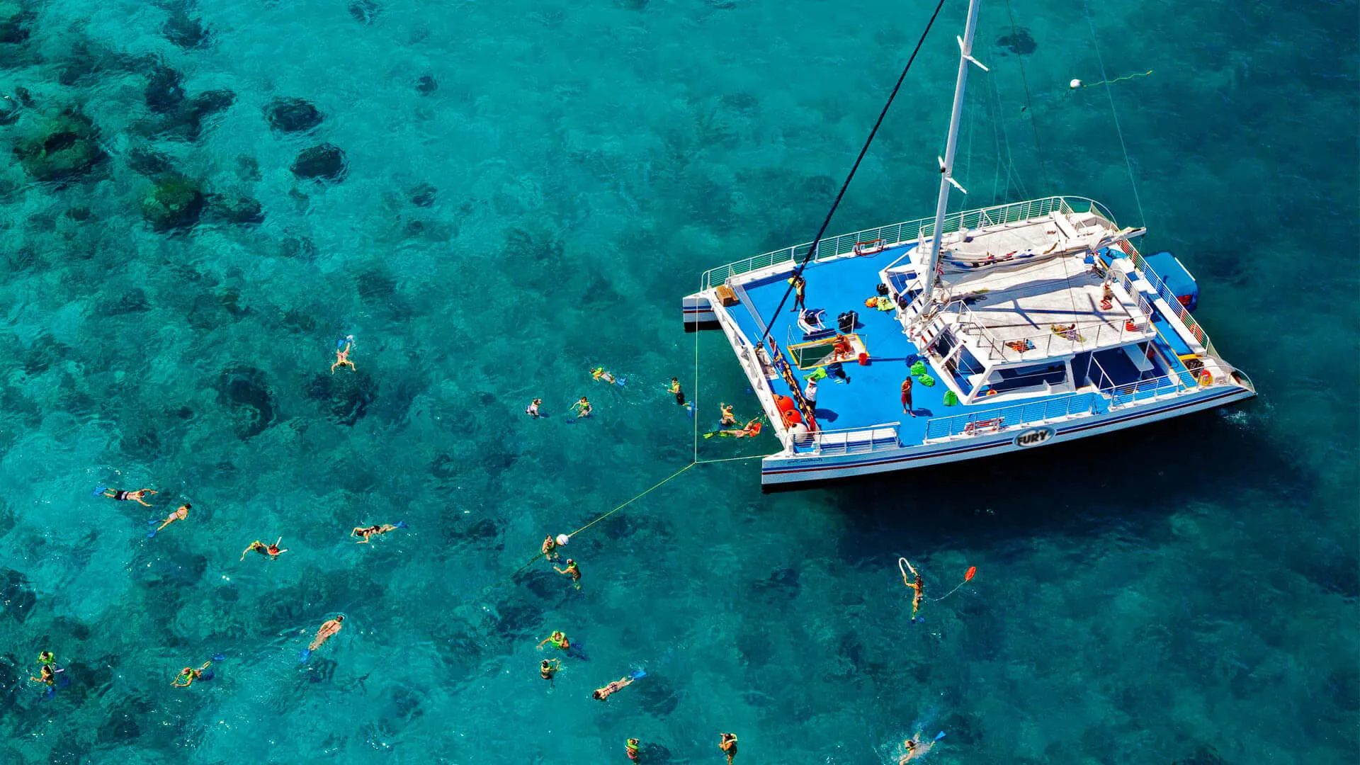 Ariel photo of the catamaran anchored over the reef with snorkelers in the water.