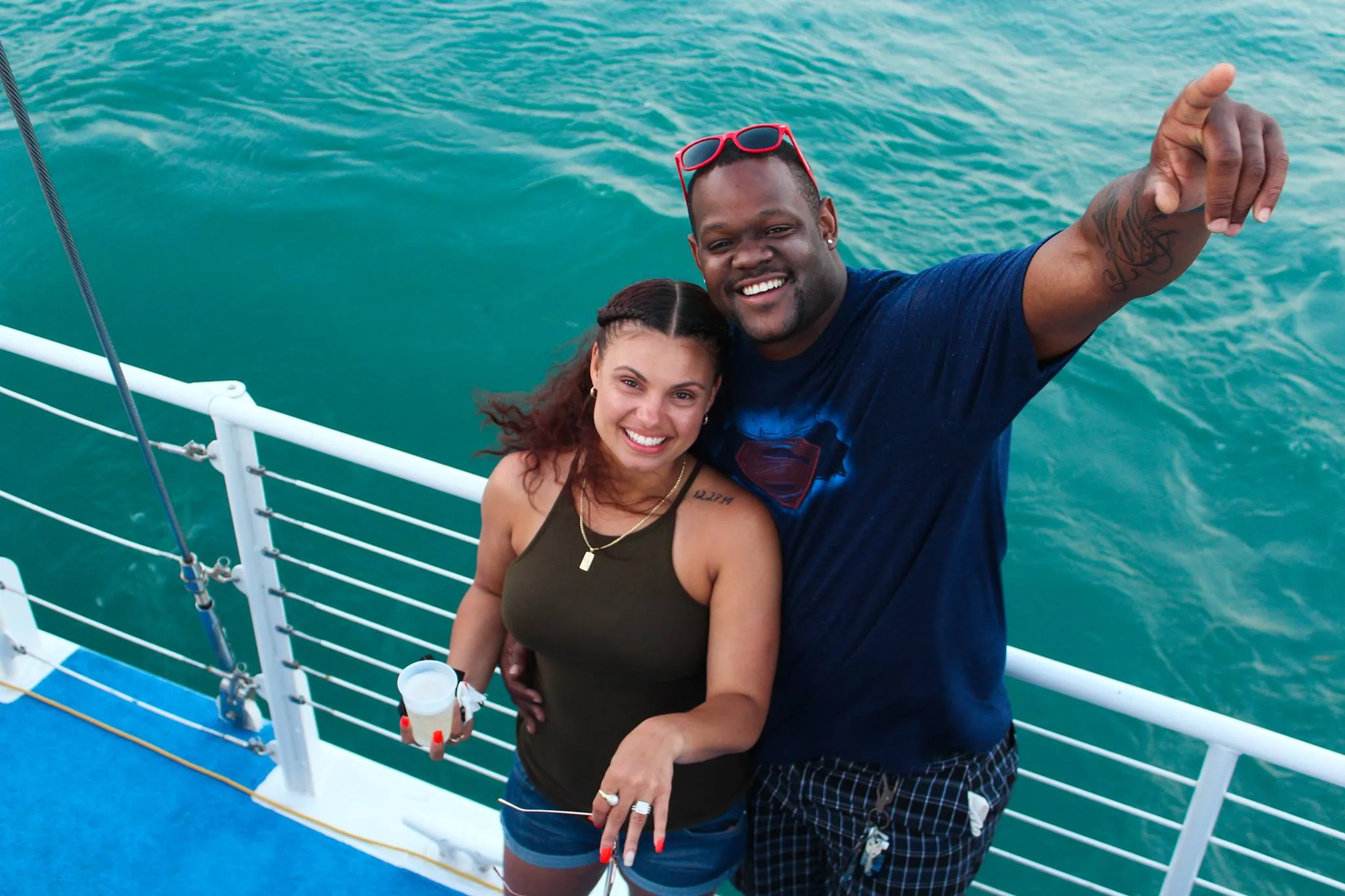 Mixed race couple on the boar raising their drinks in the air.