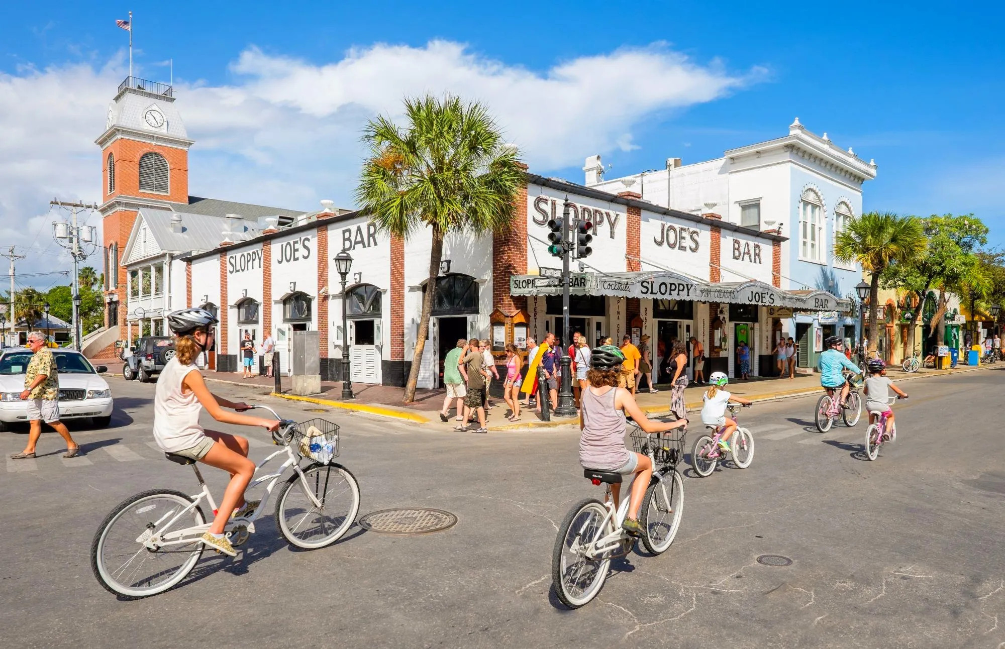Family bike ride past Sloppy Joe's bar on a sunny day.