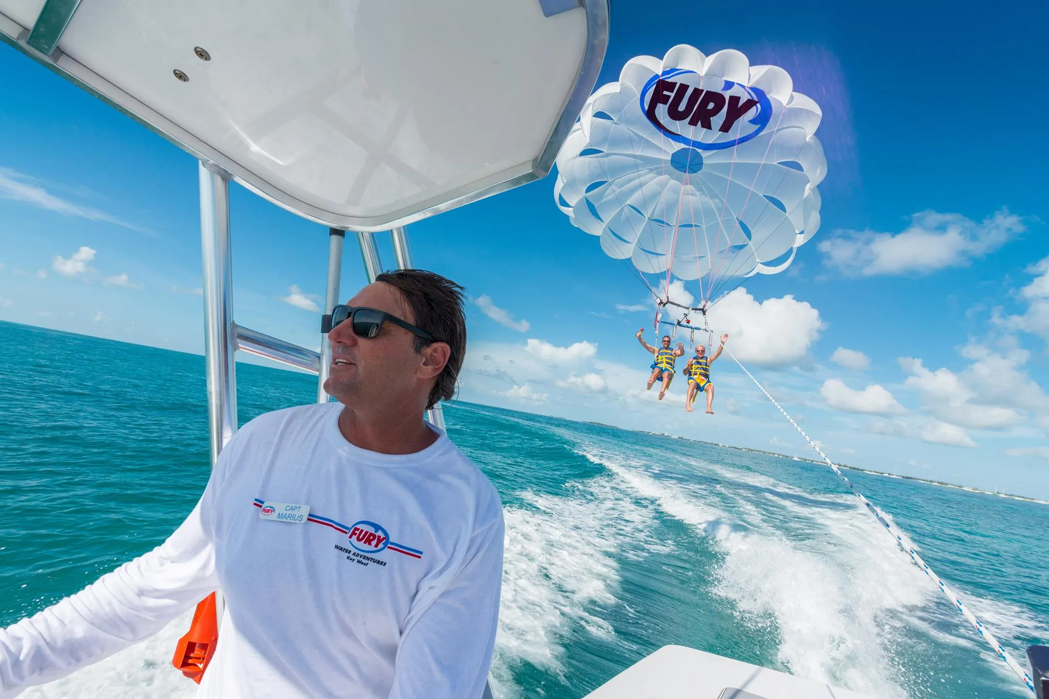 Boat captain driving the boat, with a parasail in the background.