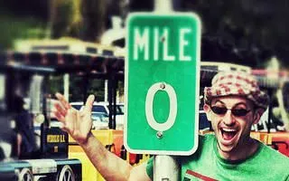 Young white man taking a silly photo at the Mile Marker 0 sign.