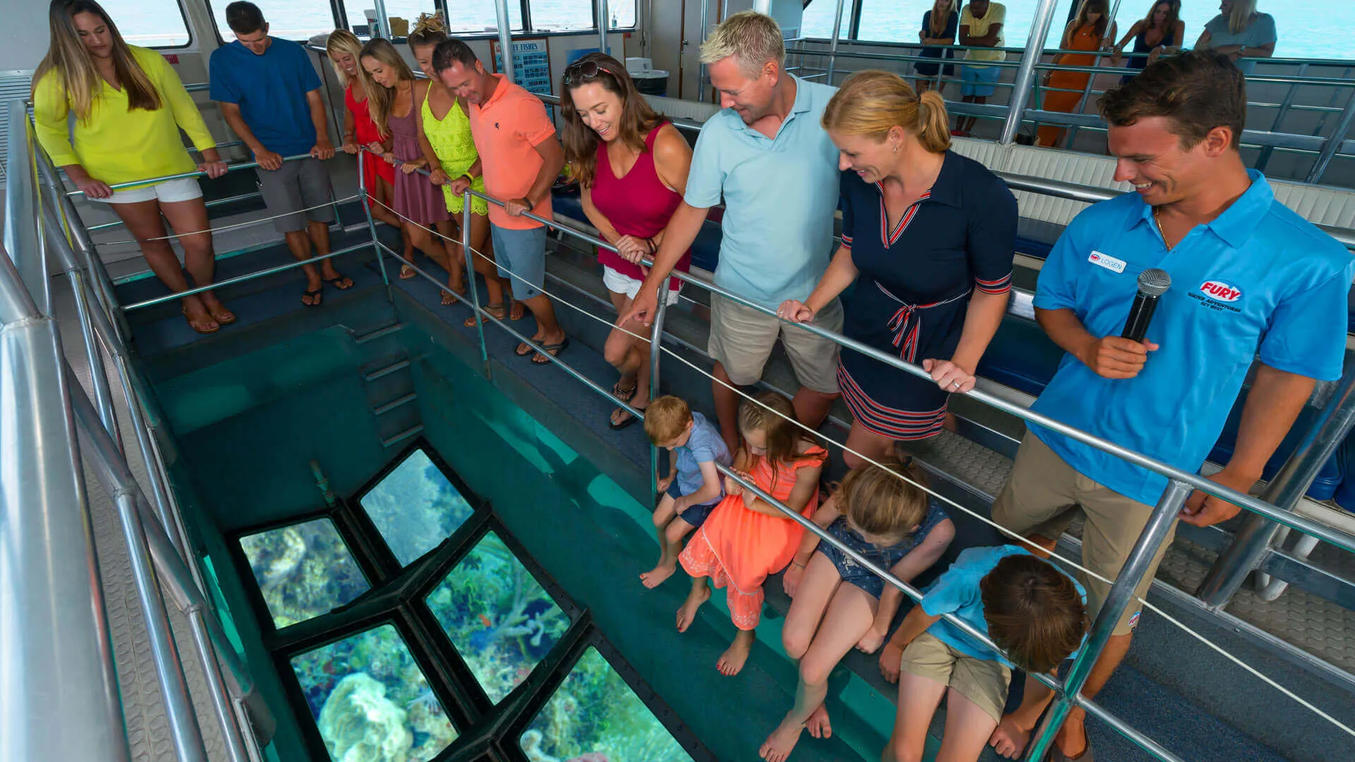 Tour group looking down the glass bottom boat at a school of fish.. 