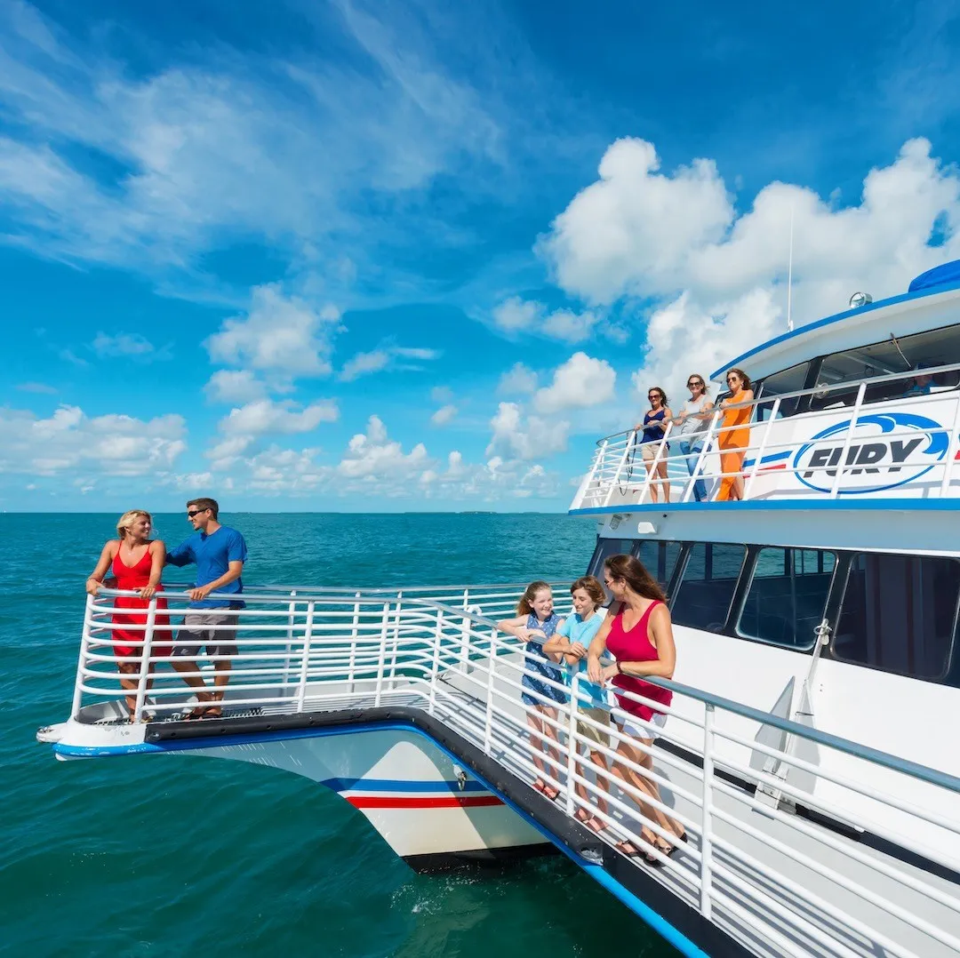 Outdoor photo of people standing on deck of the glass bottom boat on a sunny day.