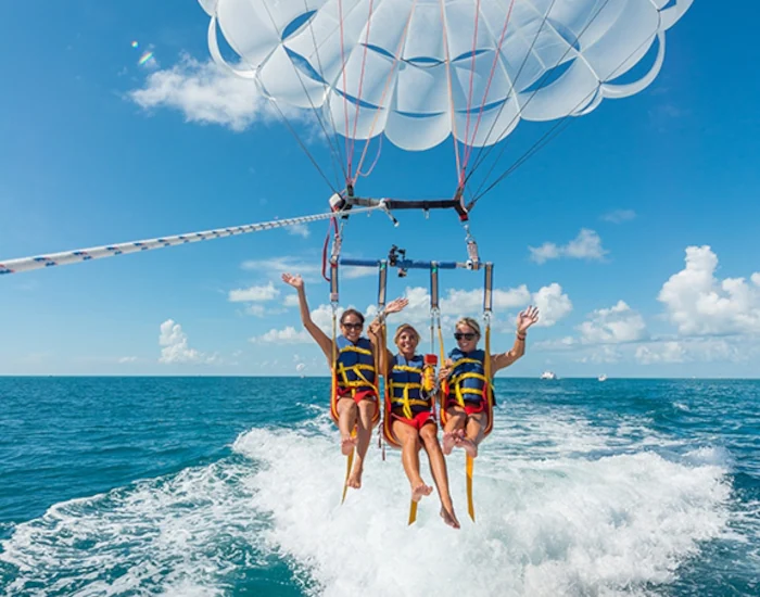 Three young ladies preparing taking off from the parasail boat.