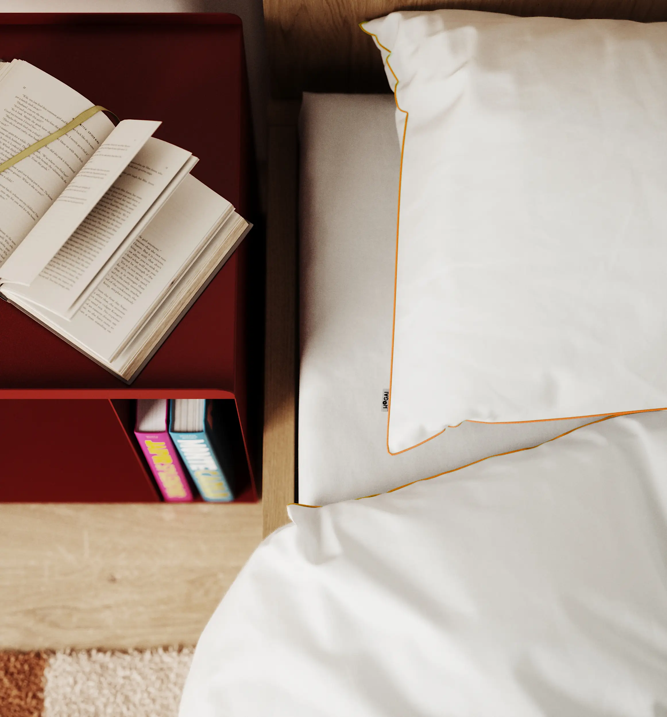 Biała pościel z żółtą lamówką w nowoczesnej sypialni obok czerwonego stolika nocnego z książkami