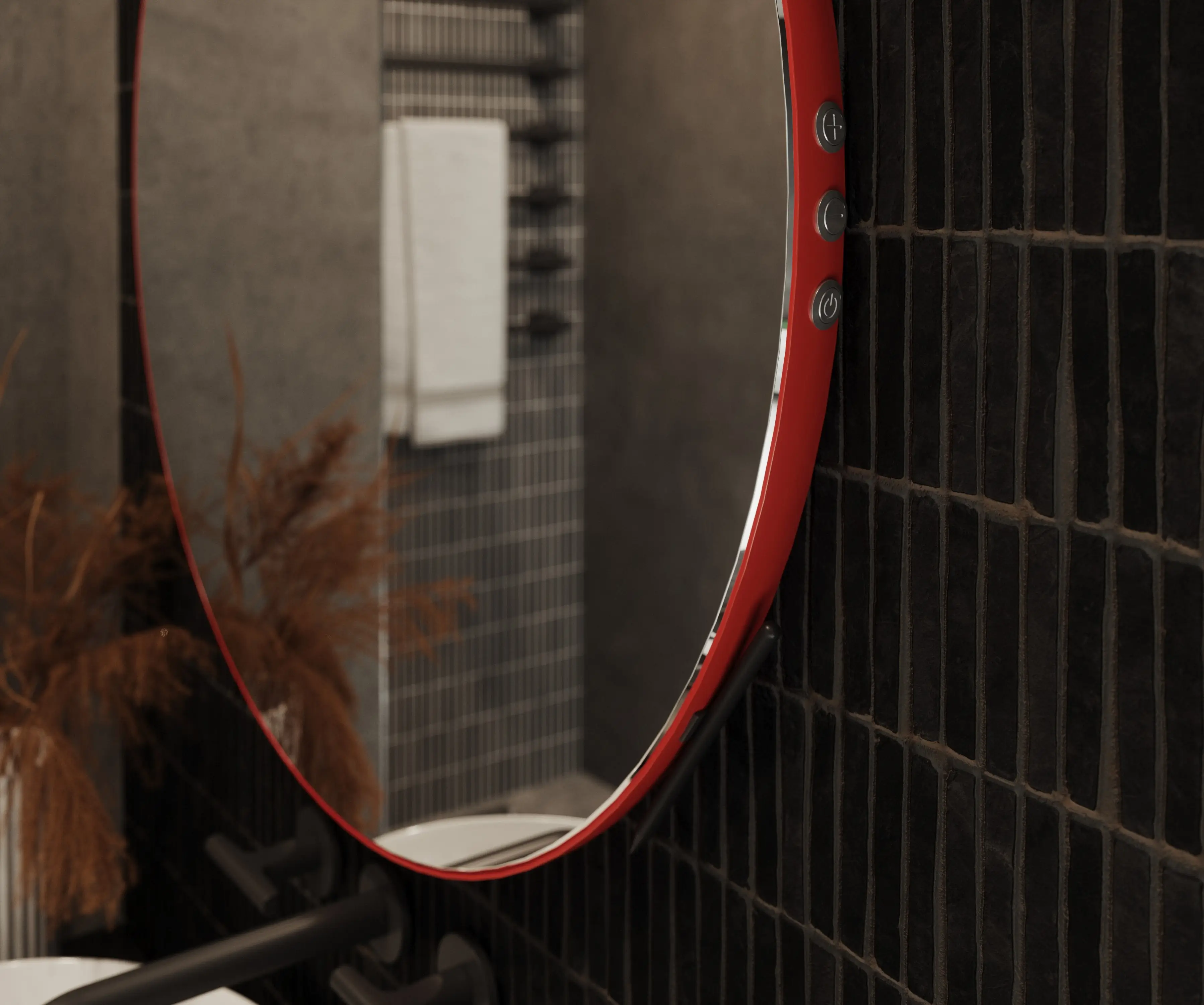 Okrągłe lustro w czerwonej ramie z wbudowanymi przyciskami dotykowymi na krawędzi, czarne kafelki w tle