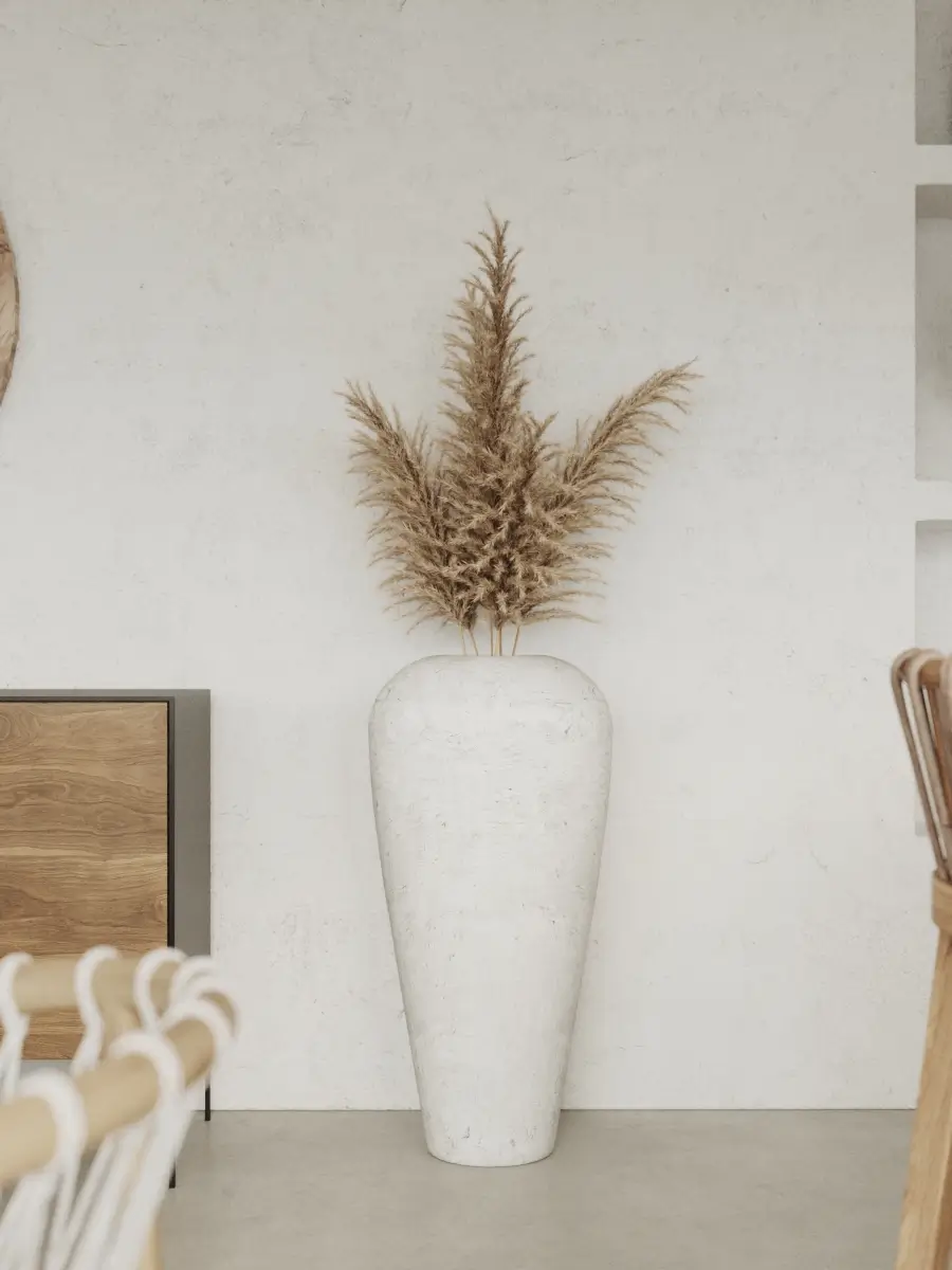 Duży biały wazon podłogowy z suszoną trawą pampasową jako element dekoracji wnętrza.