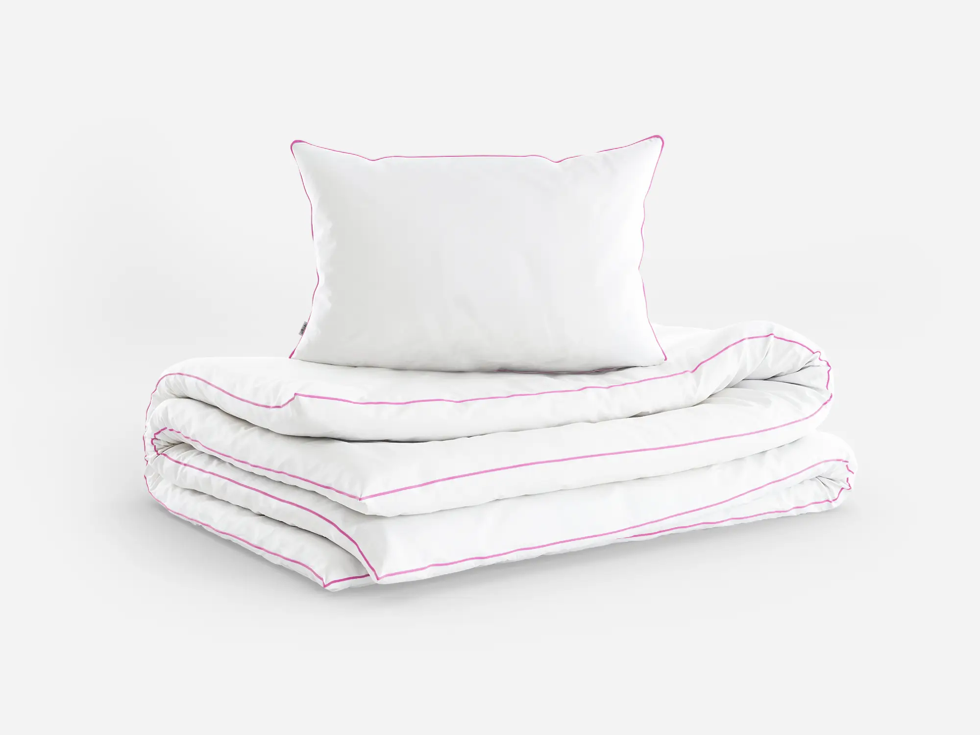 Komplet białej pościeli z różową lamówką (poduszka i kołdra) ułożony na płasko - packshot