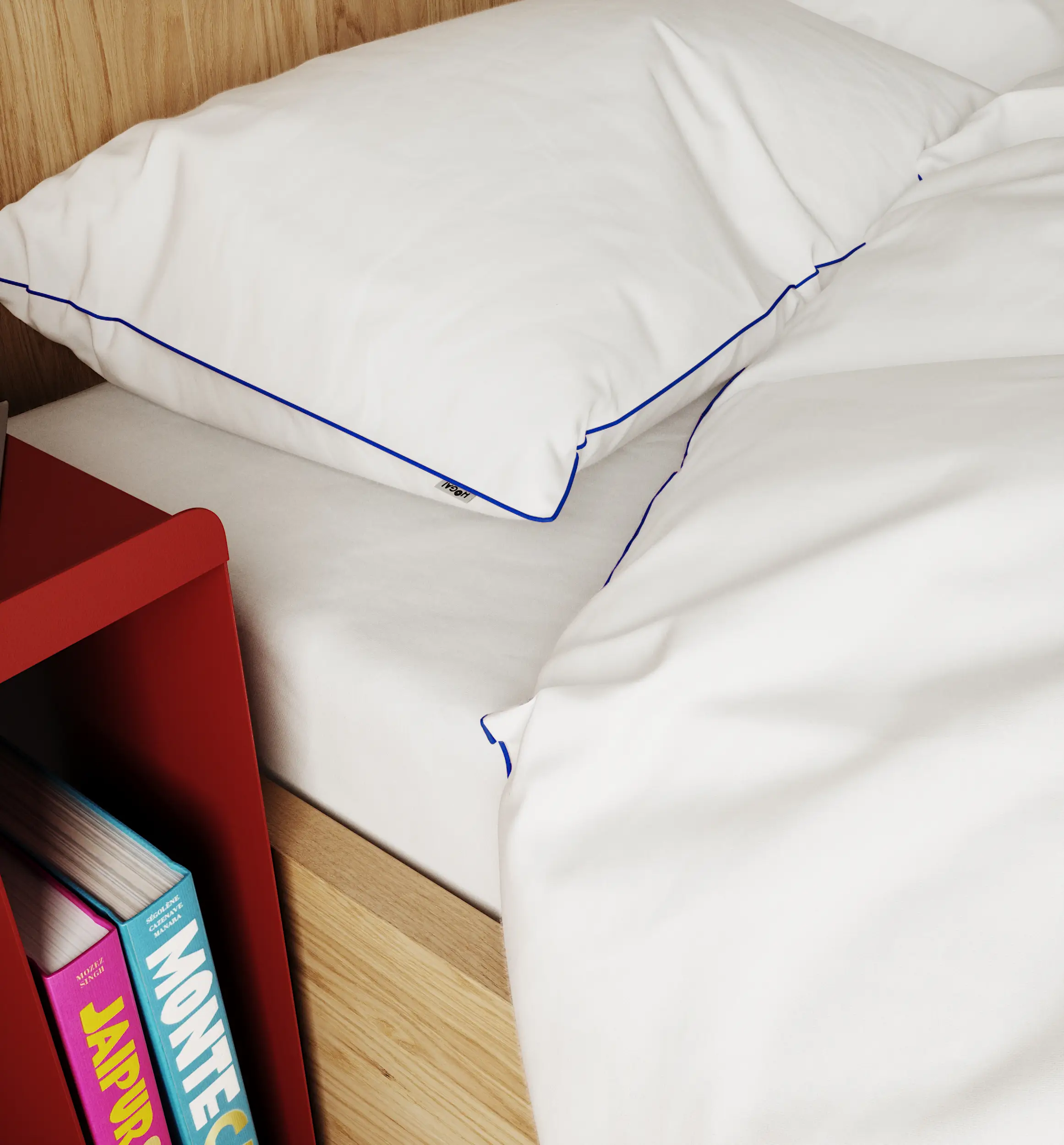 Zbliżenie na białą poduszkę i kołdrę z niebieską lamówką na drewnianym łóżku obok kolorowych książek