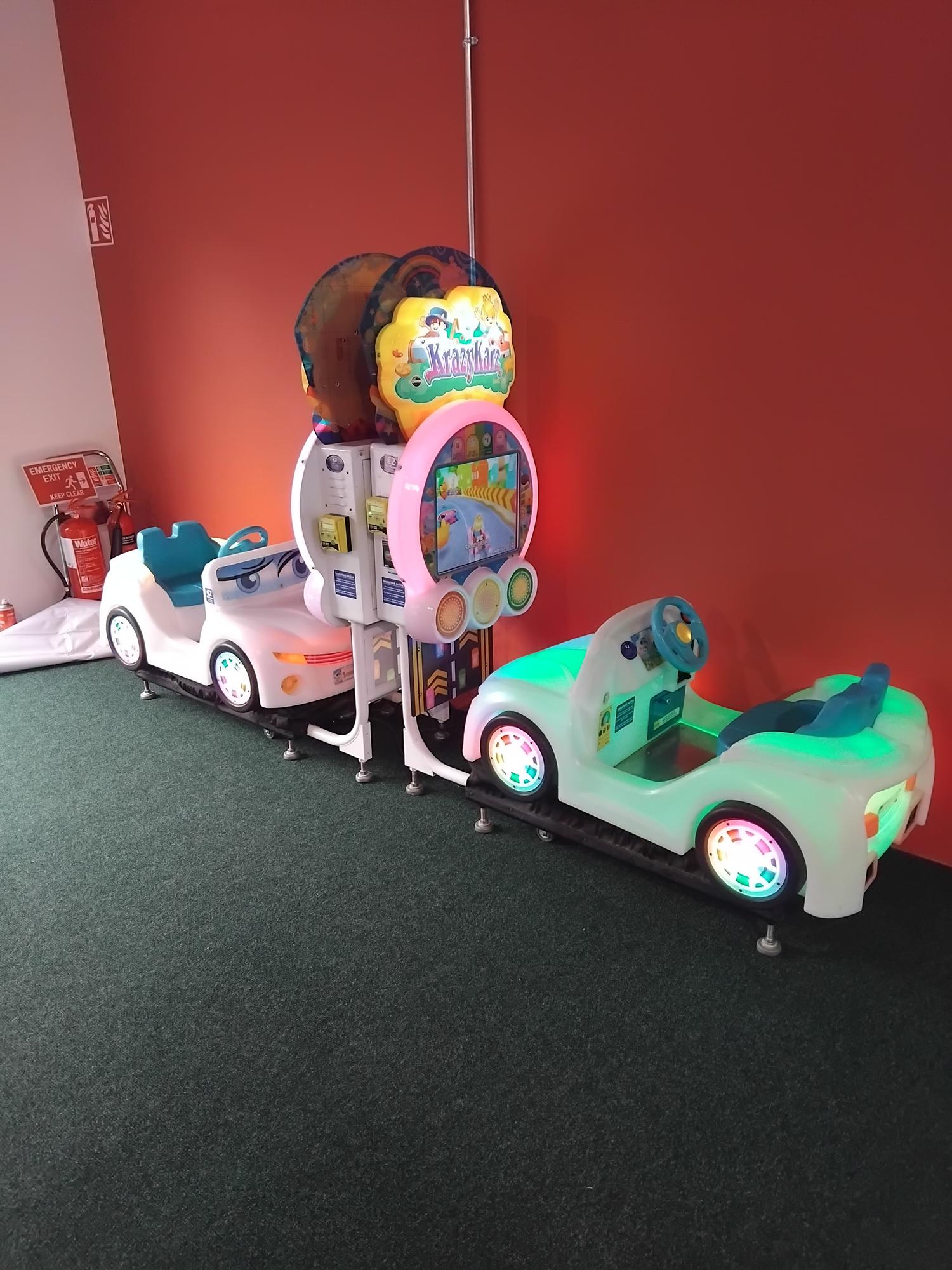 Two children's arcade rides featuring two cars with colorful LED lights and a central screen labeled 'Krazy Kartz'.