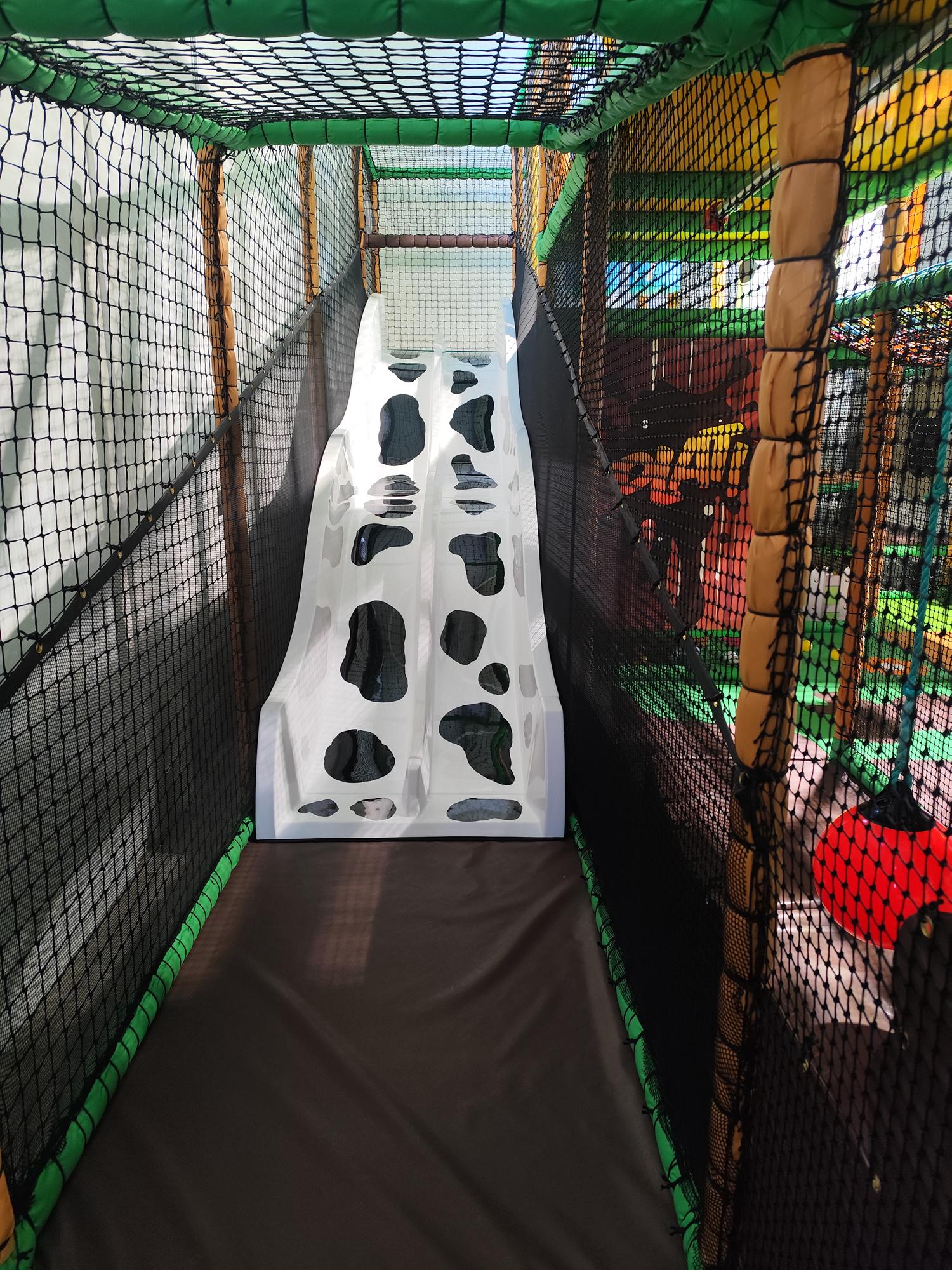 Indoor play area slide with black and white cow pattern.