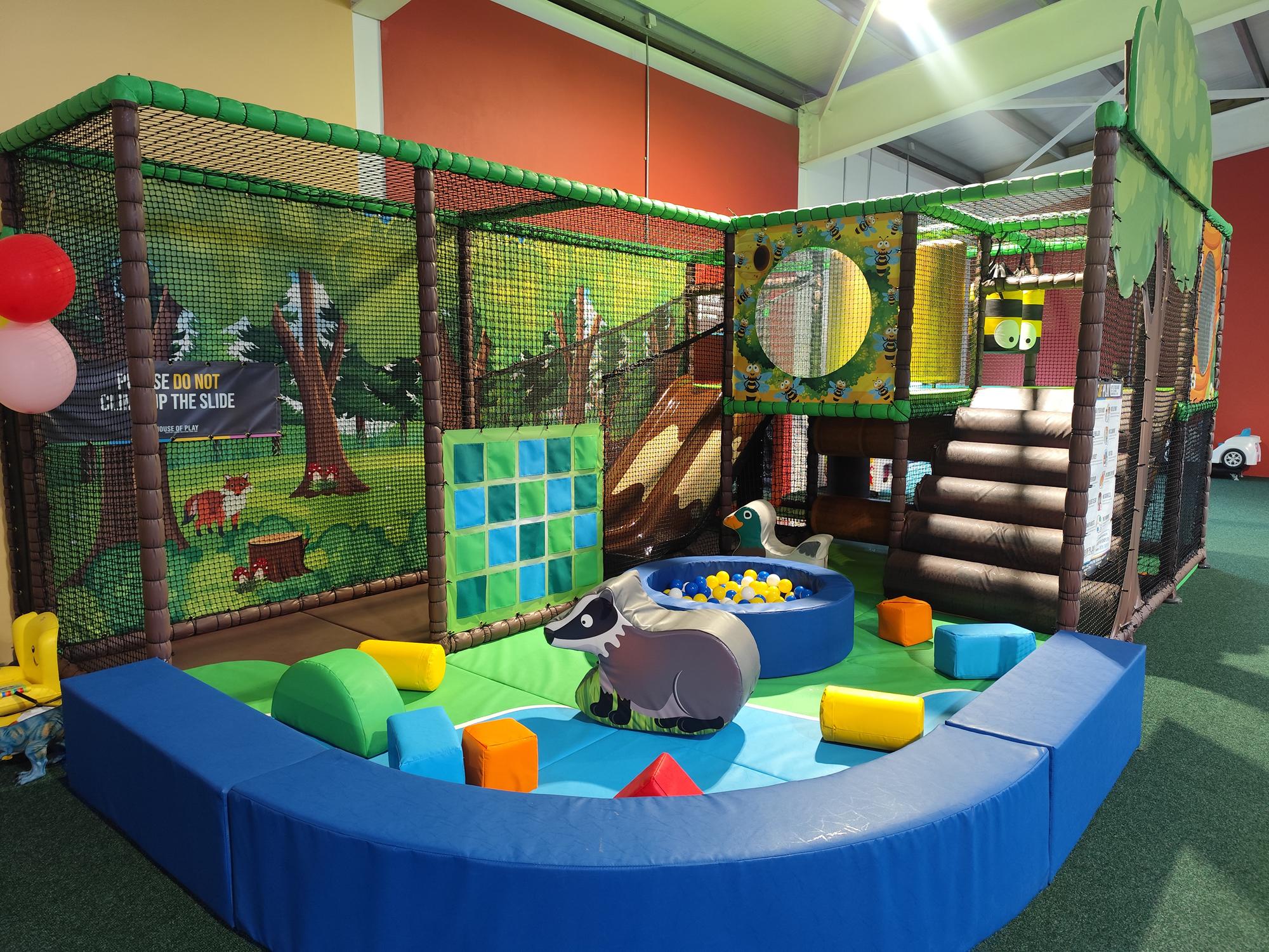 Indoor padded children's play area with soft climbing frame and animal-themed soft toys.