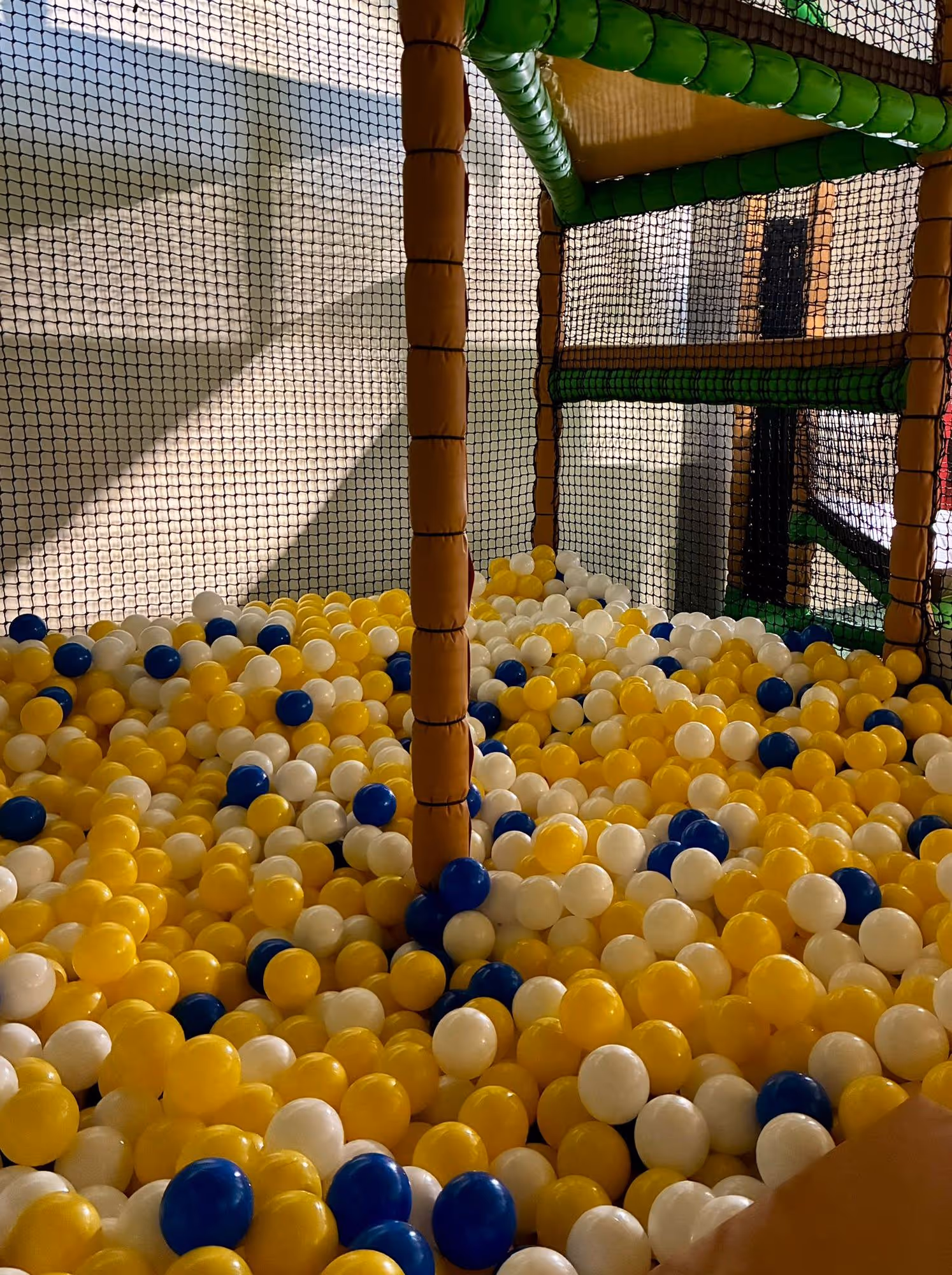 Indoor ball pit filled with yellow, white, and blue plastic balls.