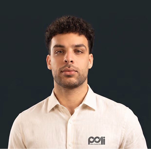 Portrait of a man with curly hair and beard wearing a black T-shirt against a black background.