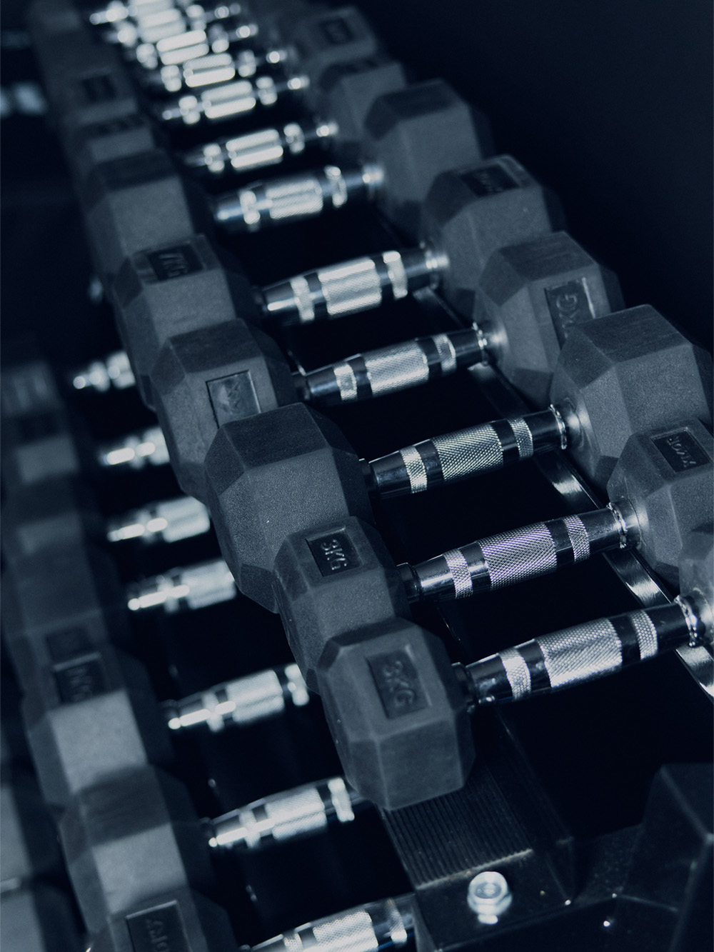 Trener wspierający kobietę w fioletowym stroju sportowym podczas ćwiczeń z hantlami.