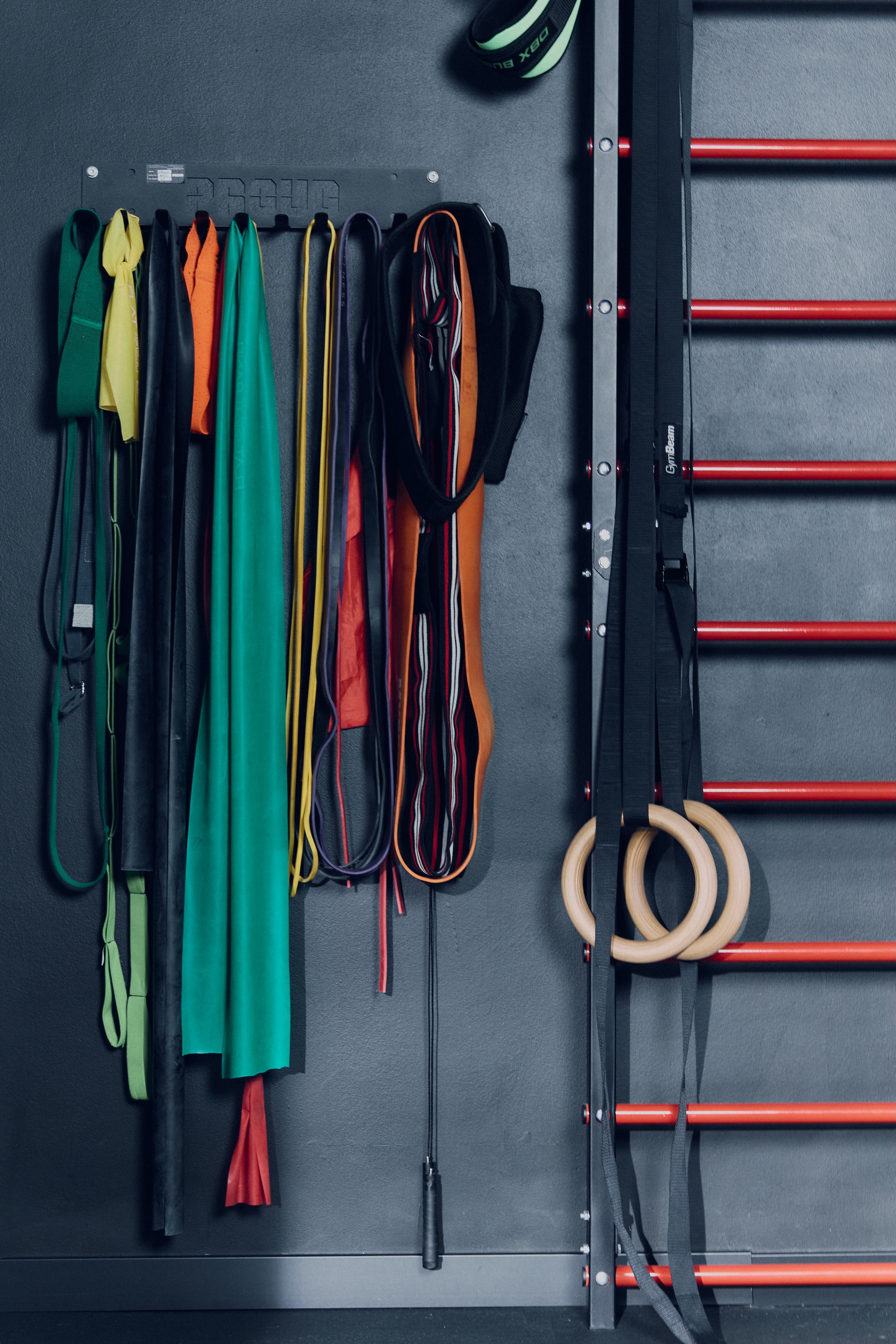 Kobieta ćwicząca rozciąganie w pozycji psa z głową w dół na macie, asystowana przez trenerkę w białej koszulce.