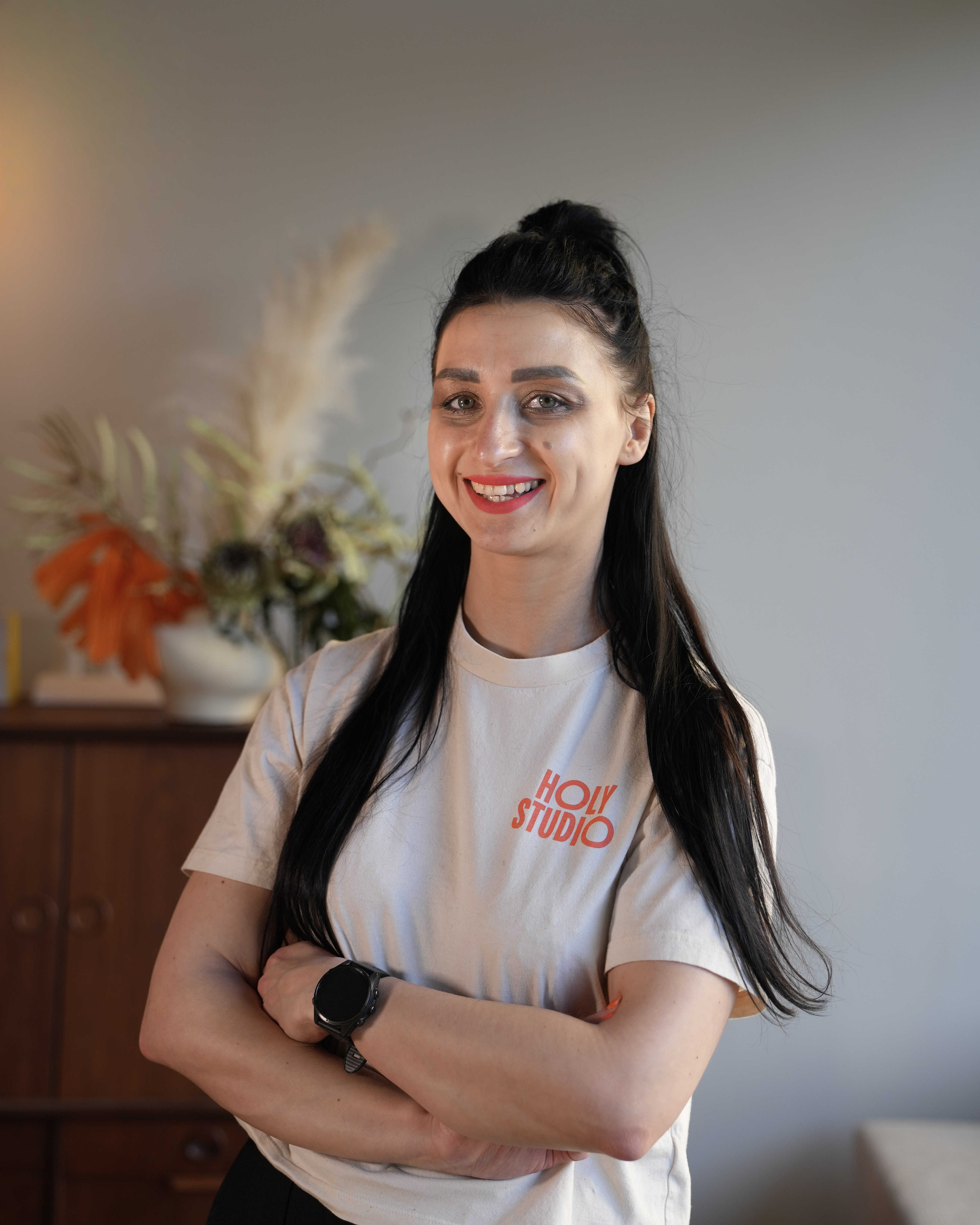 Kobieta ćwicząca rozciąganie w pozycji psa z głową w dół na macie, asystowana przez trenerkę w białej koszulce.