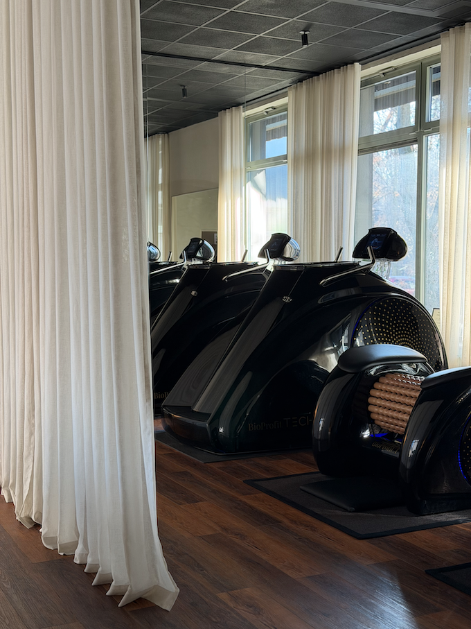 Kobieta ćwicząca rozciąganie w pozycji psa z głową w dół na macie, asystowana przez trenerkę w białej koszulce.