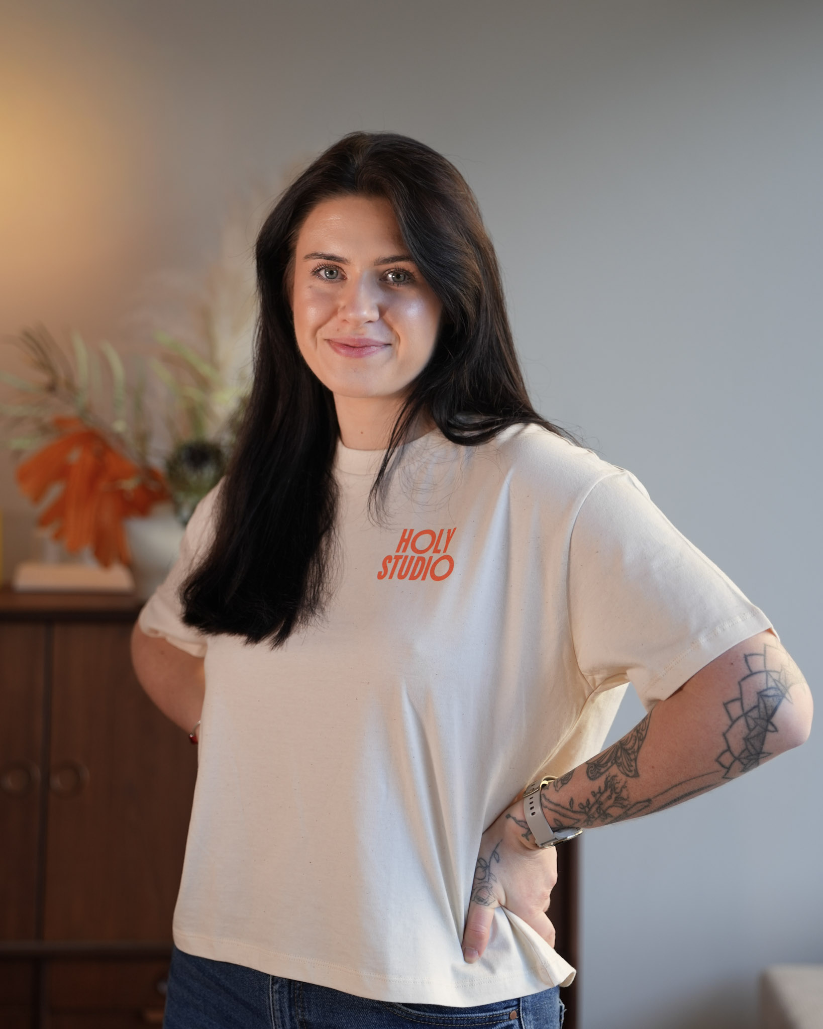 Kobieta ćwicząca rozciąganie w pozycji psa z głową w dół na macie, asystowana przez trenerkę w białej koszulce.