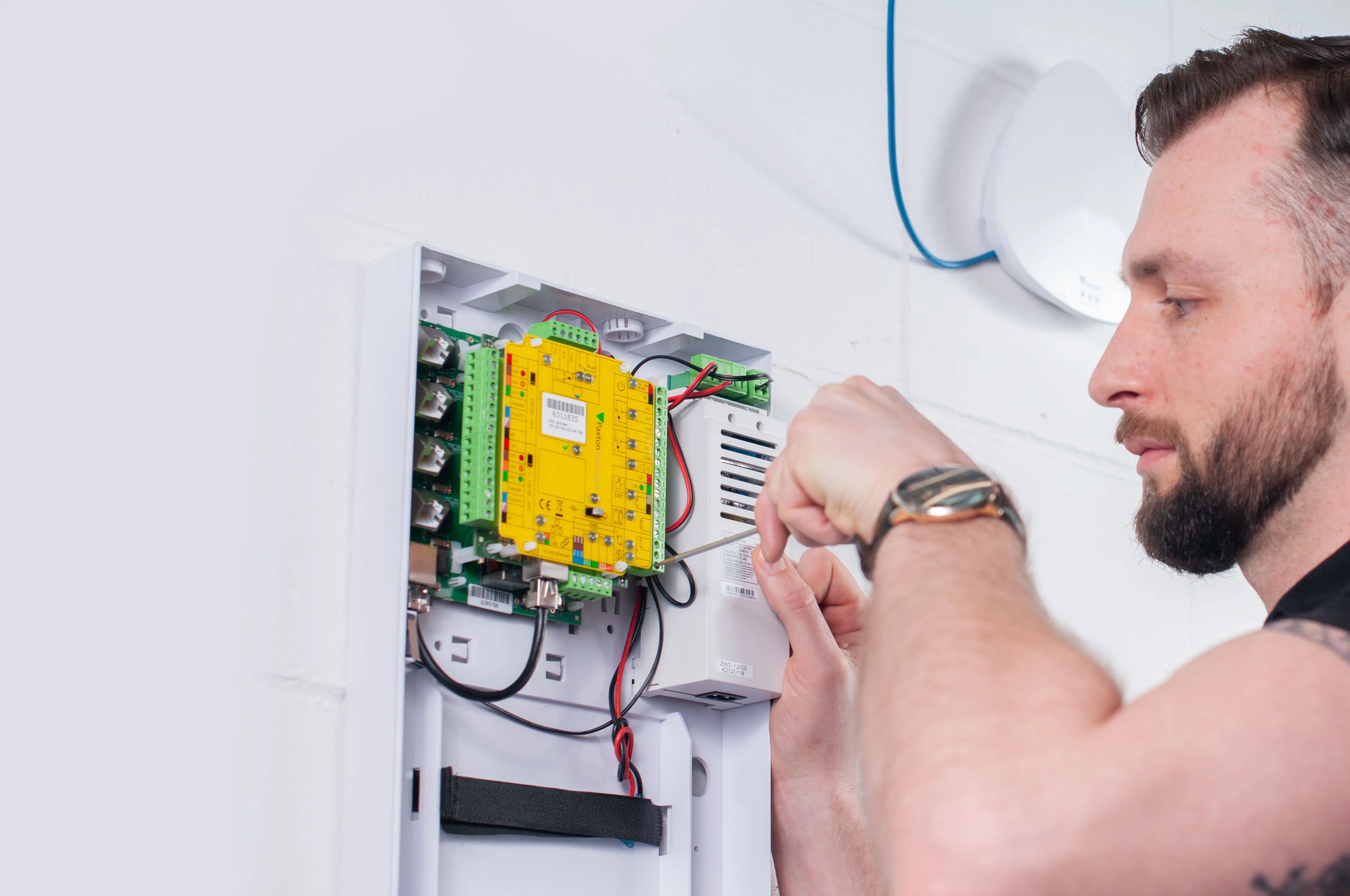 A person is installing or repairing an electrical panel on a wall.