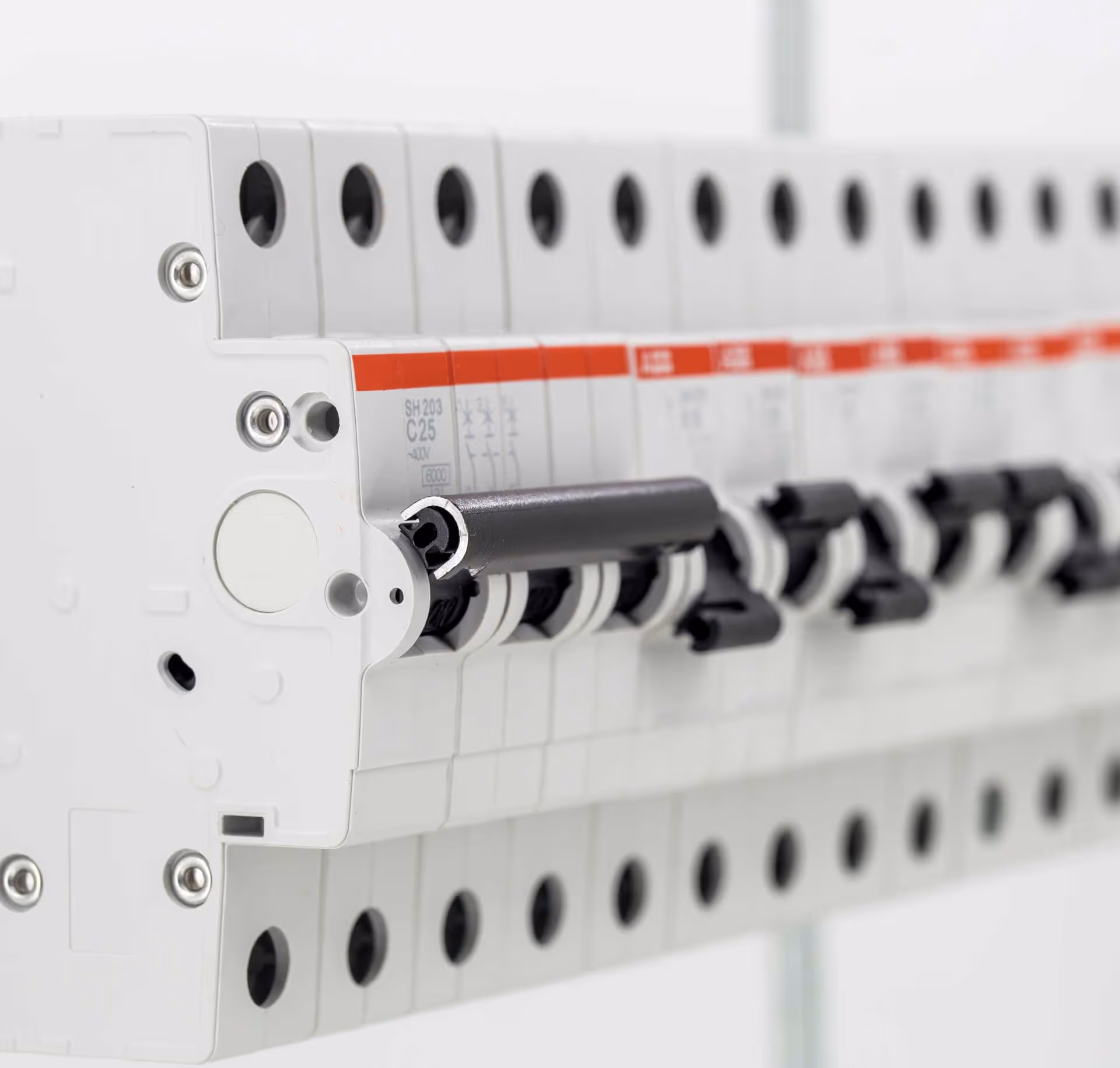 A row of electrical circuit breakers mounted on a panel with switches in the off position.
