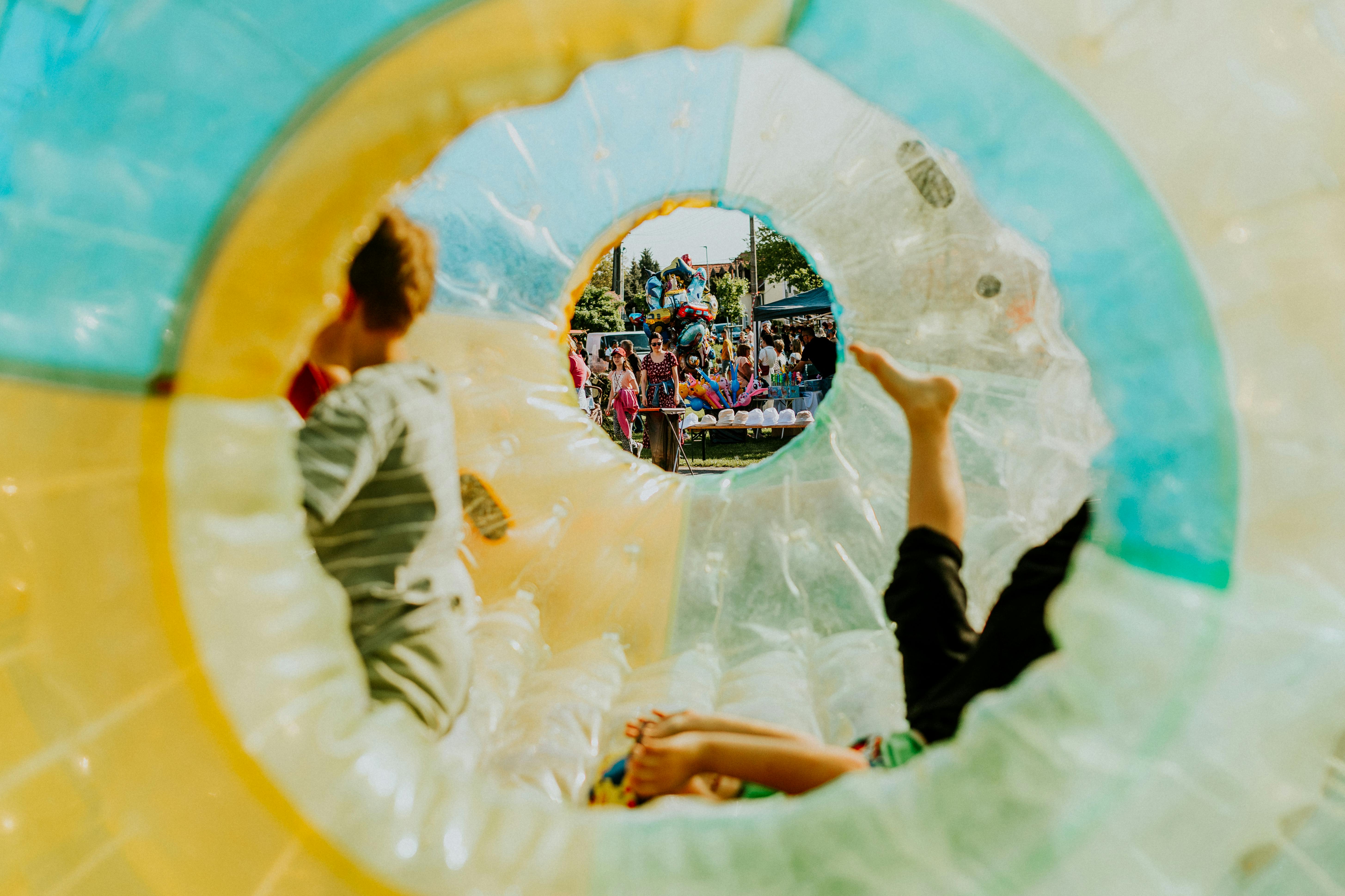 Groupe d'enfants souriants appuyés sur une barrière colorée dans un parc ensoleillé.