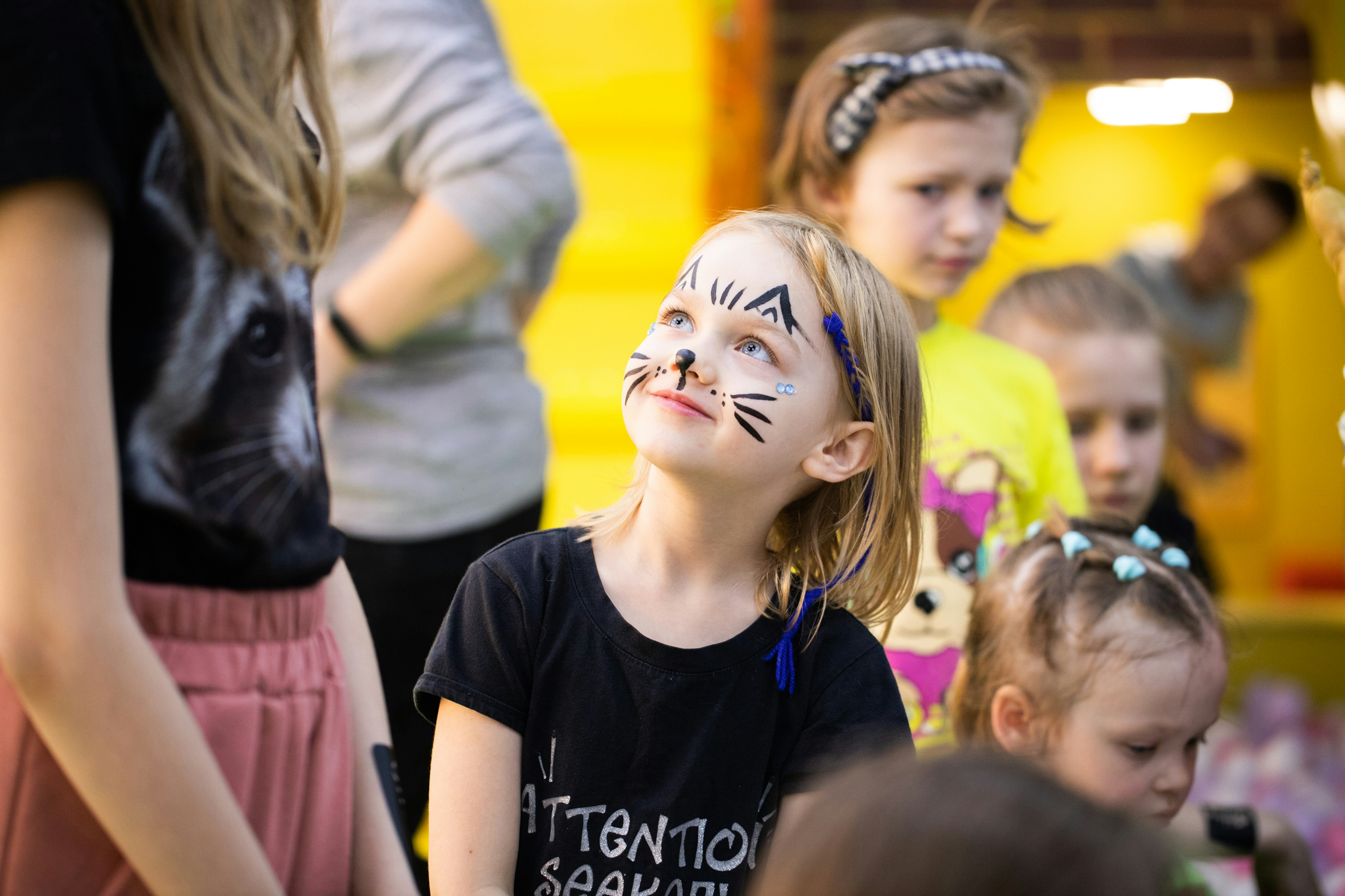 Groupe d'enfants souriants appuyés sur une barrière colorée dans un parc ensoleillé.