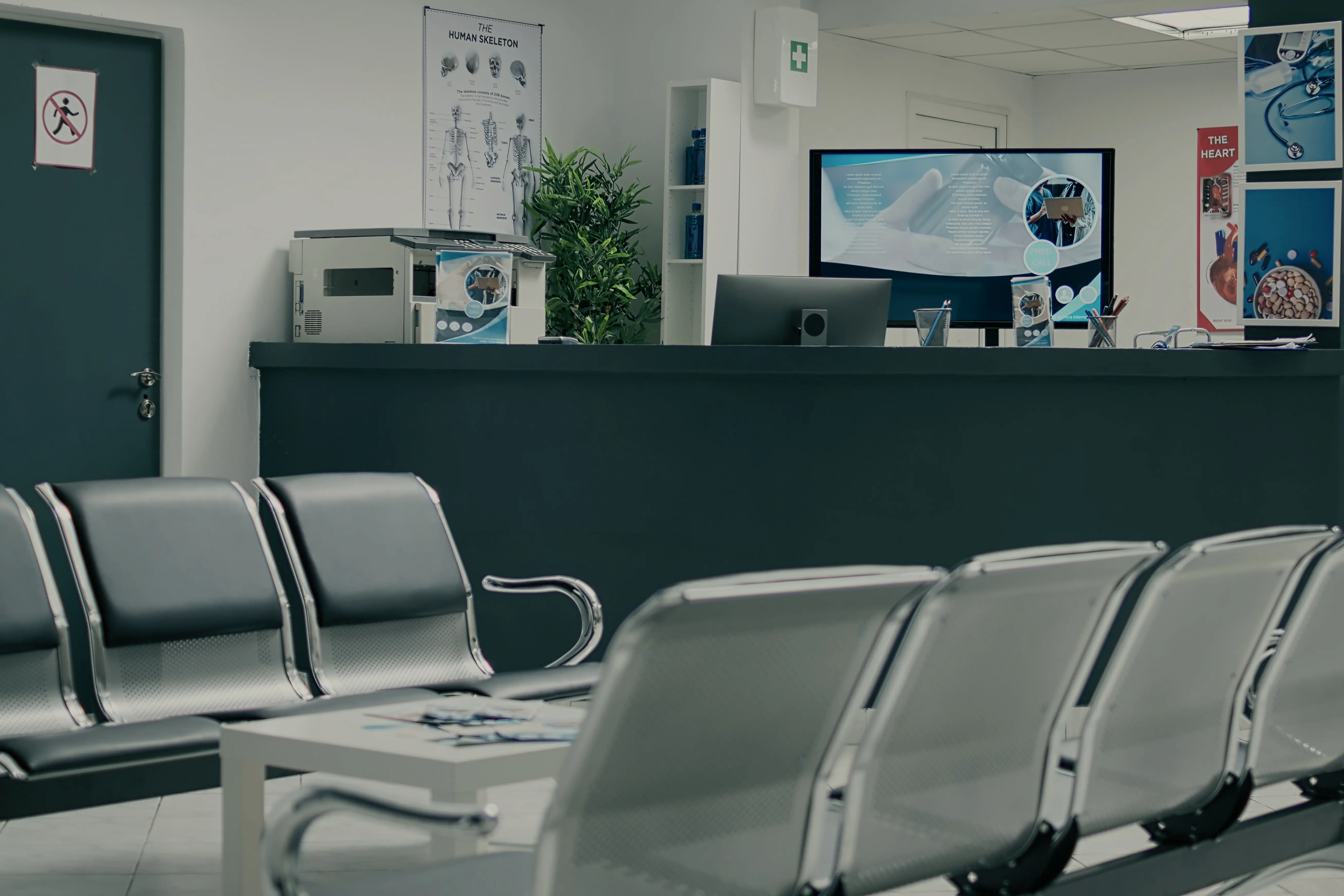 Modern clinic reception area with a white desk, circular ceiling lights, glass doors, and two navy blue sofas facing opposite directions.