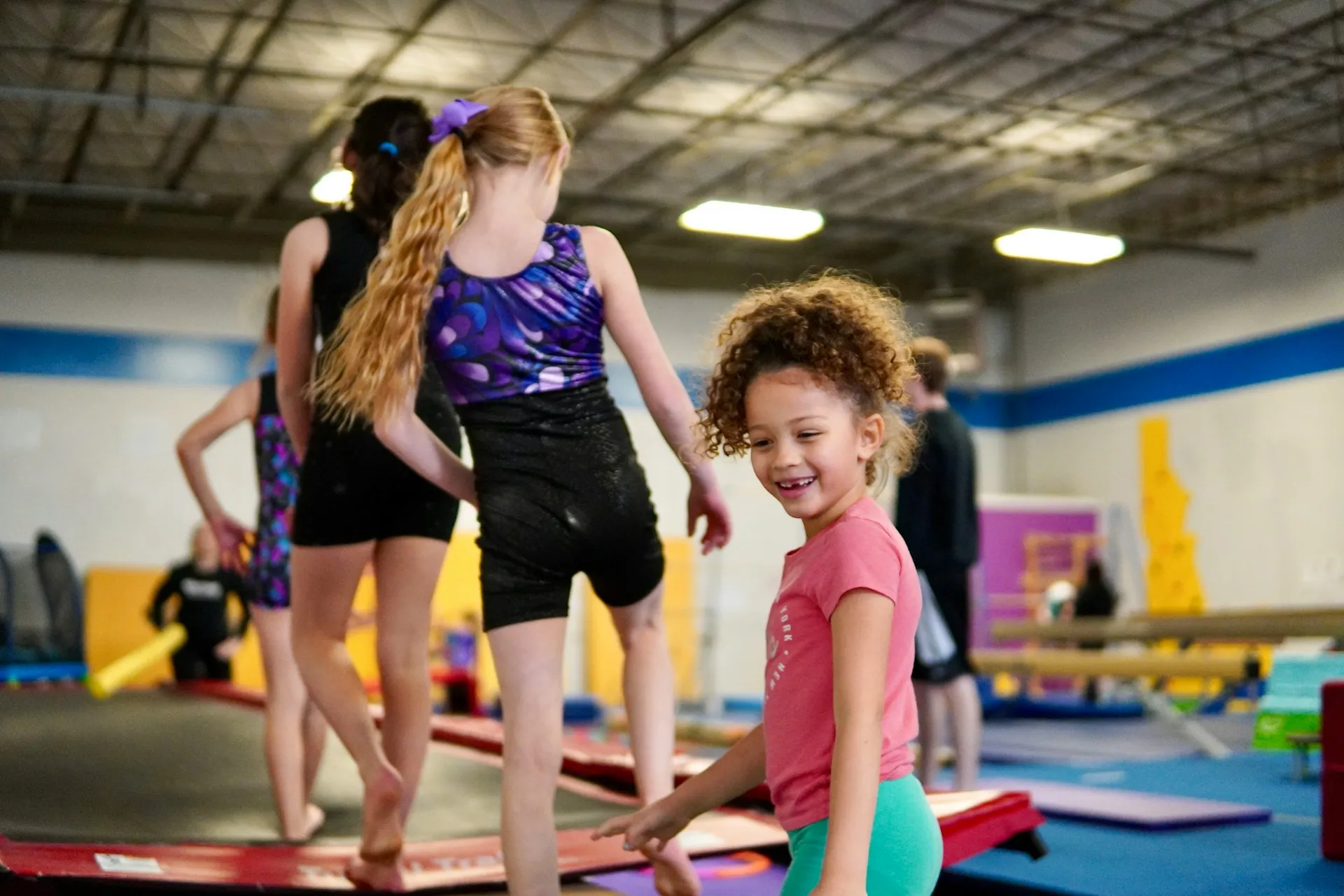 Young girls exercising on gym mats in a gymnastics training facility.