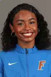 Smiling young woman with curly hair wearing a blue sports jacket with an F logo.