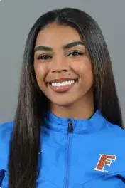 Smiling woman with long black hair wearing a blue jacket with an F logo on the left side.