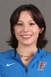 Smiling young woman with short dark hair wearing a blue Nike jacket with an F logo.