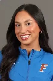 Smiling woman with long dark hair wearing a blue jacket with an 'F' logo on it.