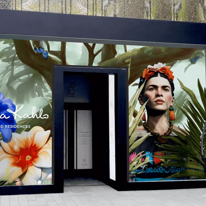 Building entrance decorated with a mural featuring Frida Kahlo's portrait with flowers and greenery around her.