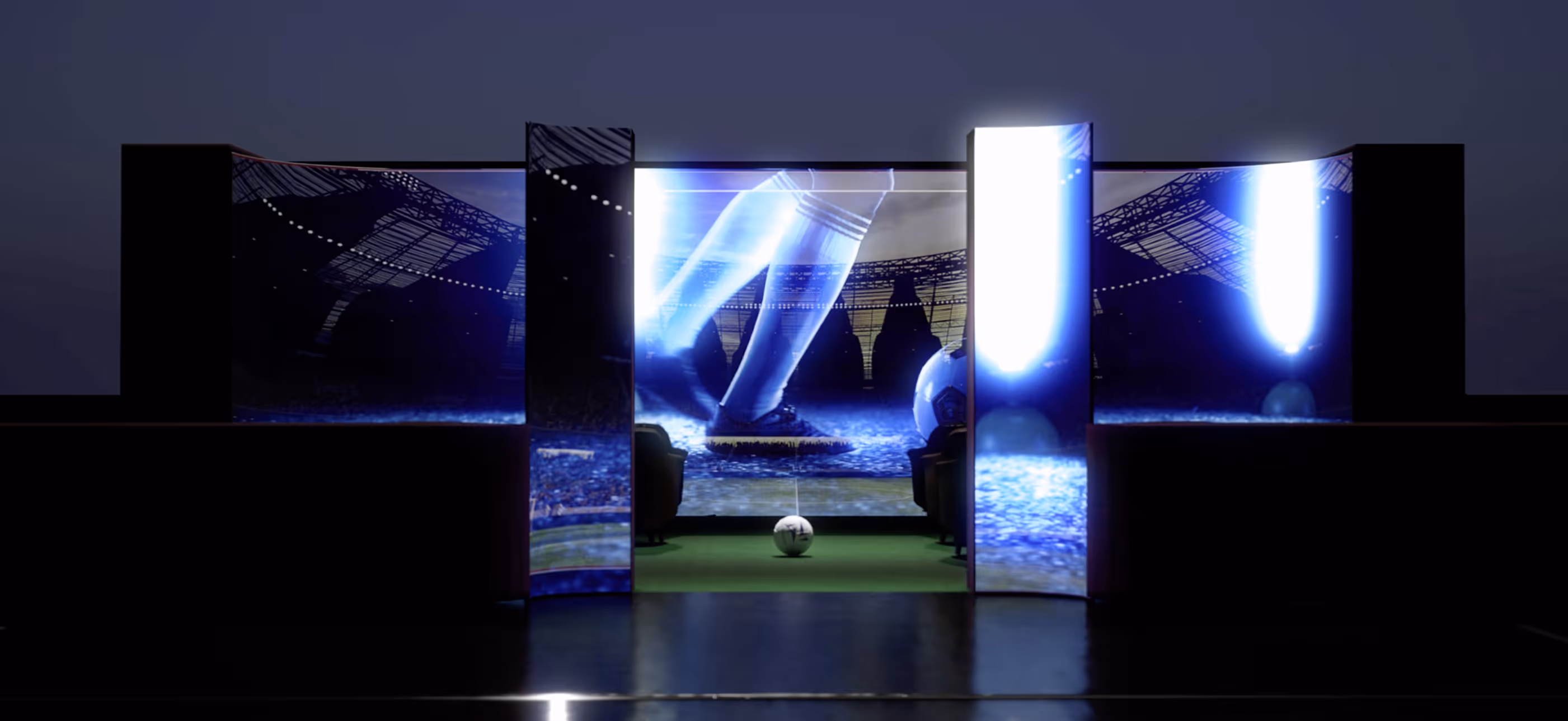 Soccer ball on green field facing curved translucent screen with city skyline in dimly lit room.