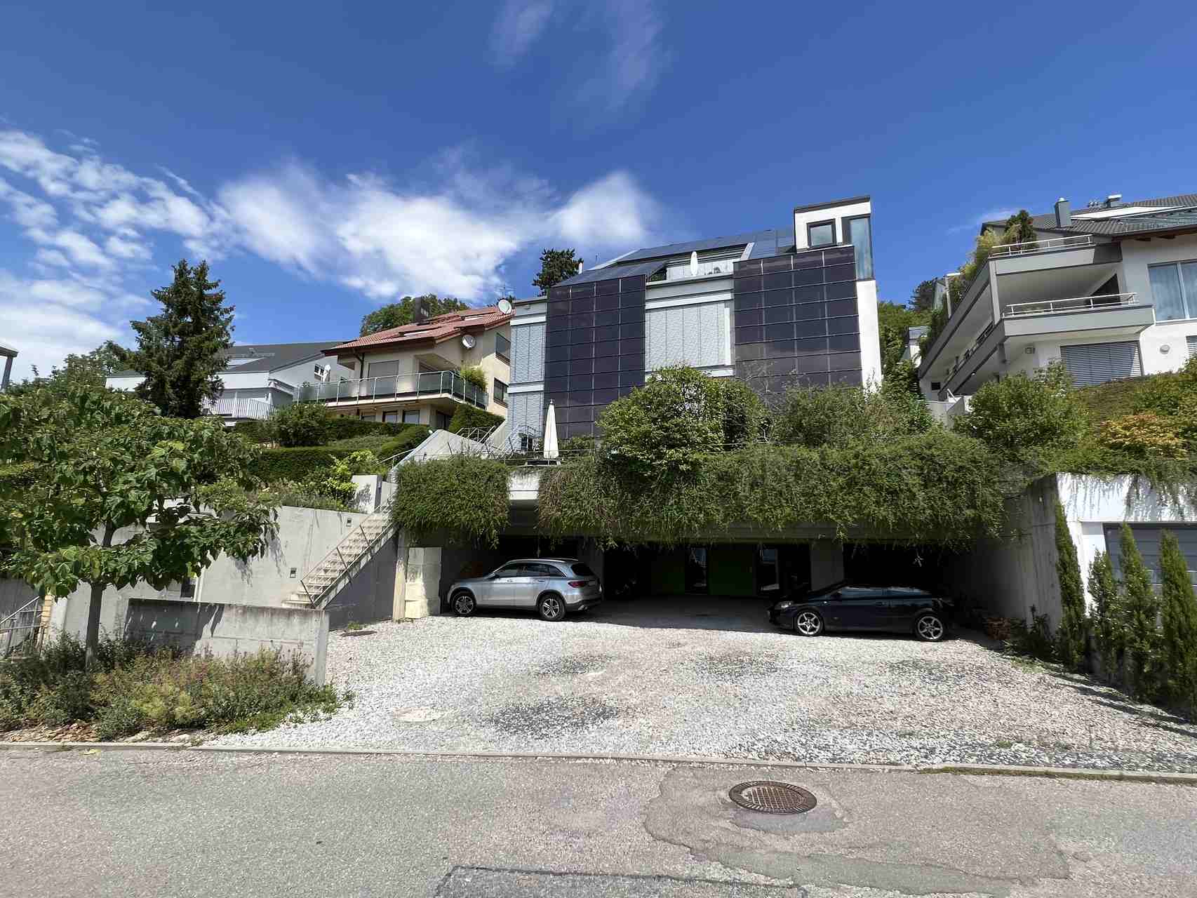 Haus mit Photovoltaik an der Fassade und ein groĂźer Parkplatz davor
