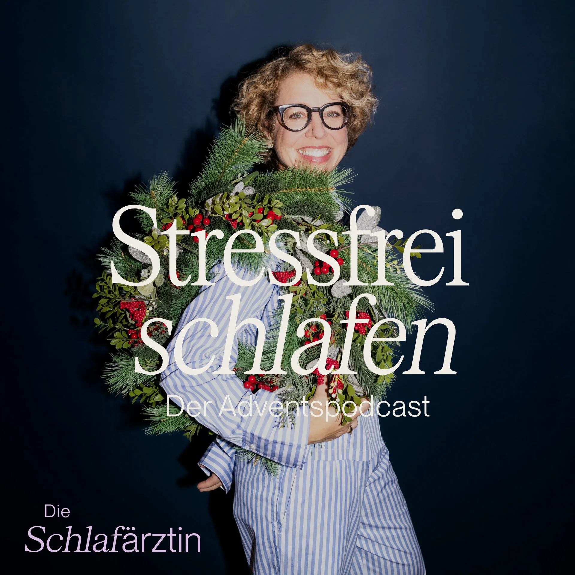 Lächelnde Frau in gestreiftem Pyjama trägt einen Weihnachtskranz mit Tannenzweigen und roten Beeren vor dunkelblauem Hintergrund.