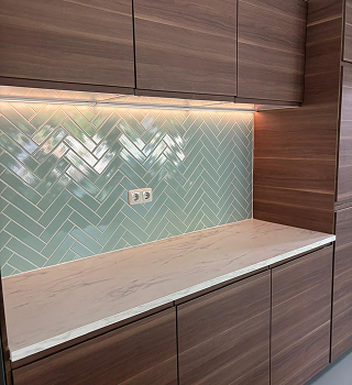 Snelle renovatie van de keuken met plaatsing van pastelgroene tegels en vernieuwde afwerking.