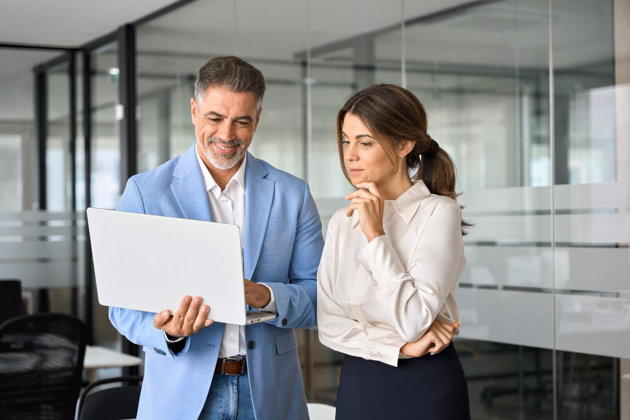 Two professionals reviewing information on a laptop during an office meeting.