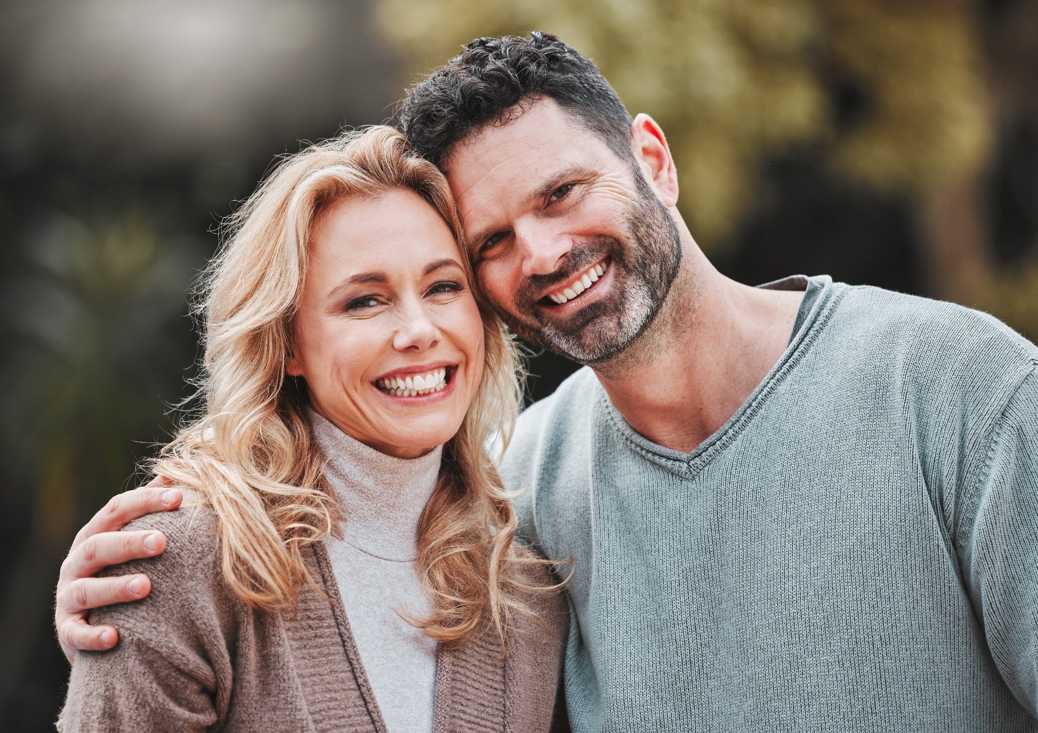 a smiling middle-aged couple standing closely together outdoors