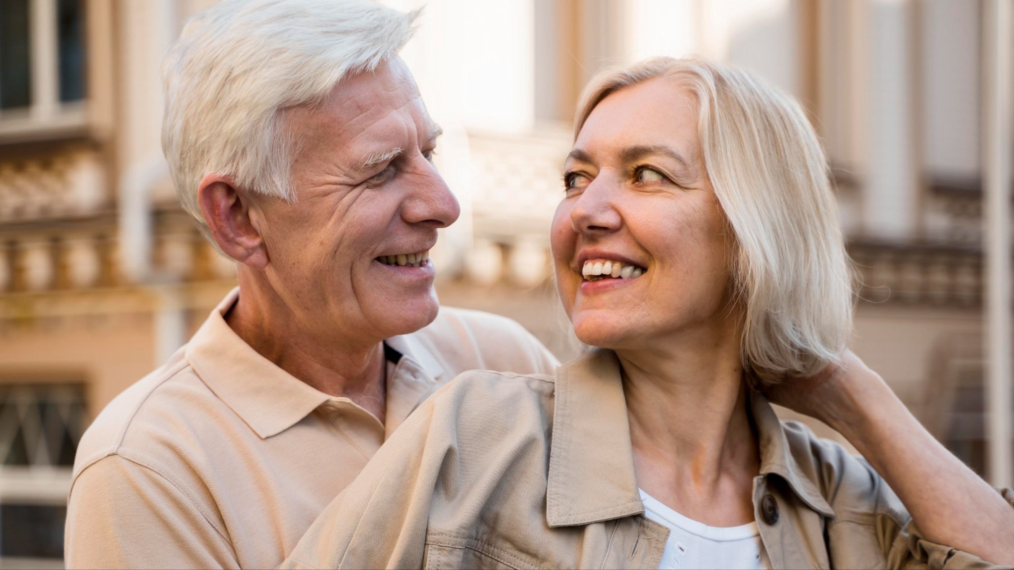 older couple smiling and looking at each other affectionately in an outdoor setting.