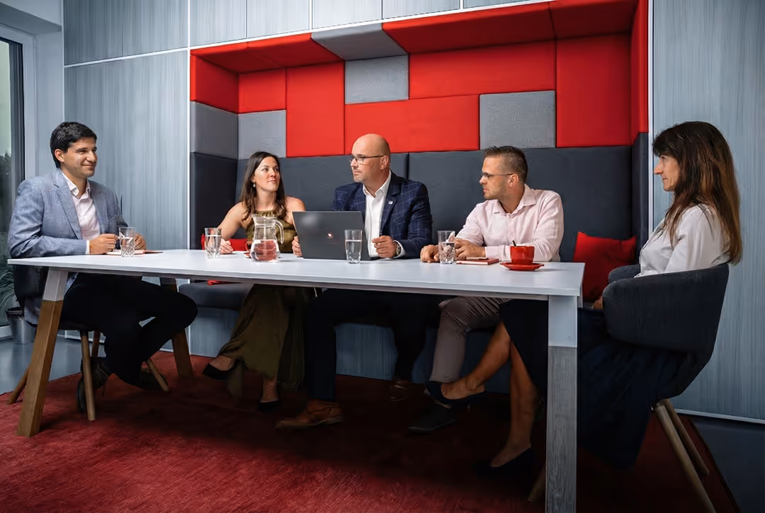 Profesionální a usměvavý tým specialistů pojišťovacího makléře Eurovalley při společné pracovní konzultaci v moderním kancelářském zázemí.