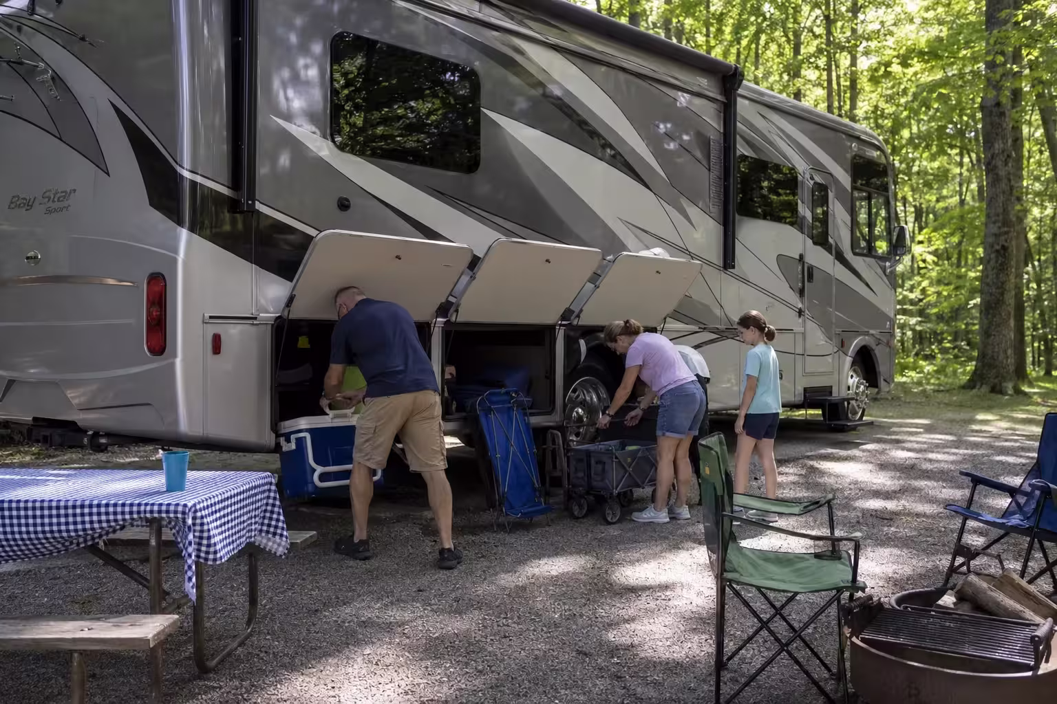 Family loading gear into a Class A motorhome at a Finger Lakes campground