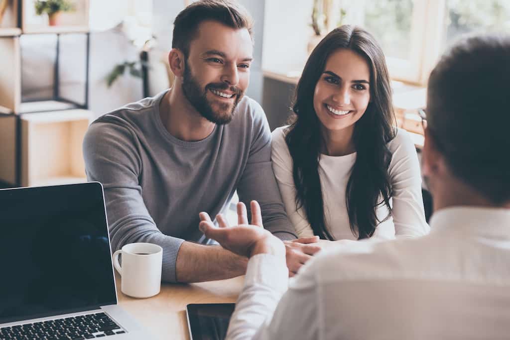 Smiling couple sitting at a table during a consultation with a professional.