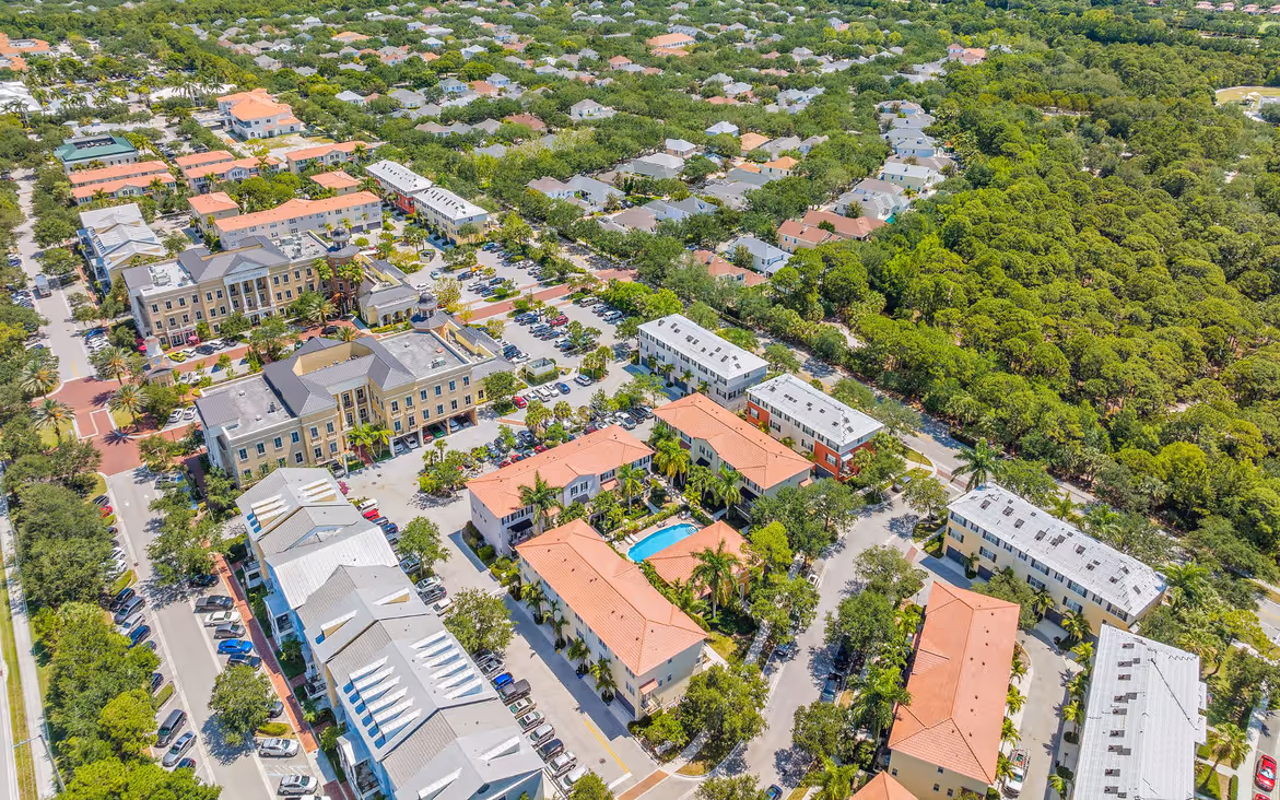 Aerial view of a residential neighborhood with apartment buildings, houses, parking lots, and green trees.